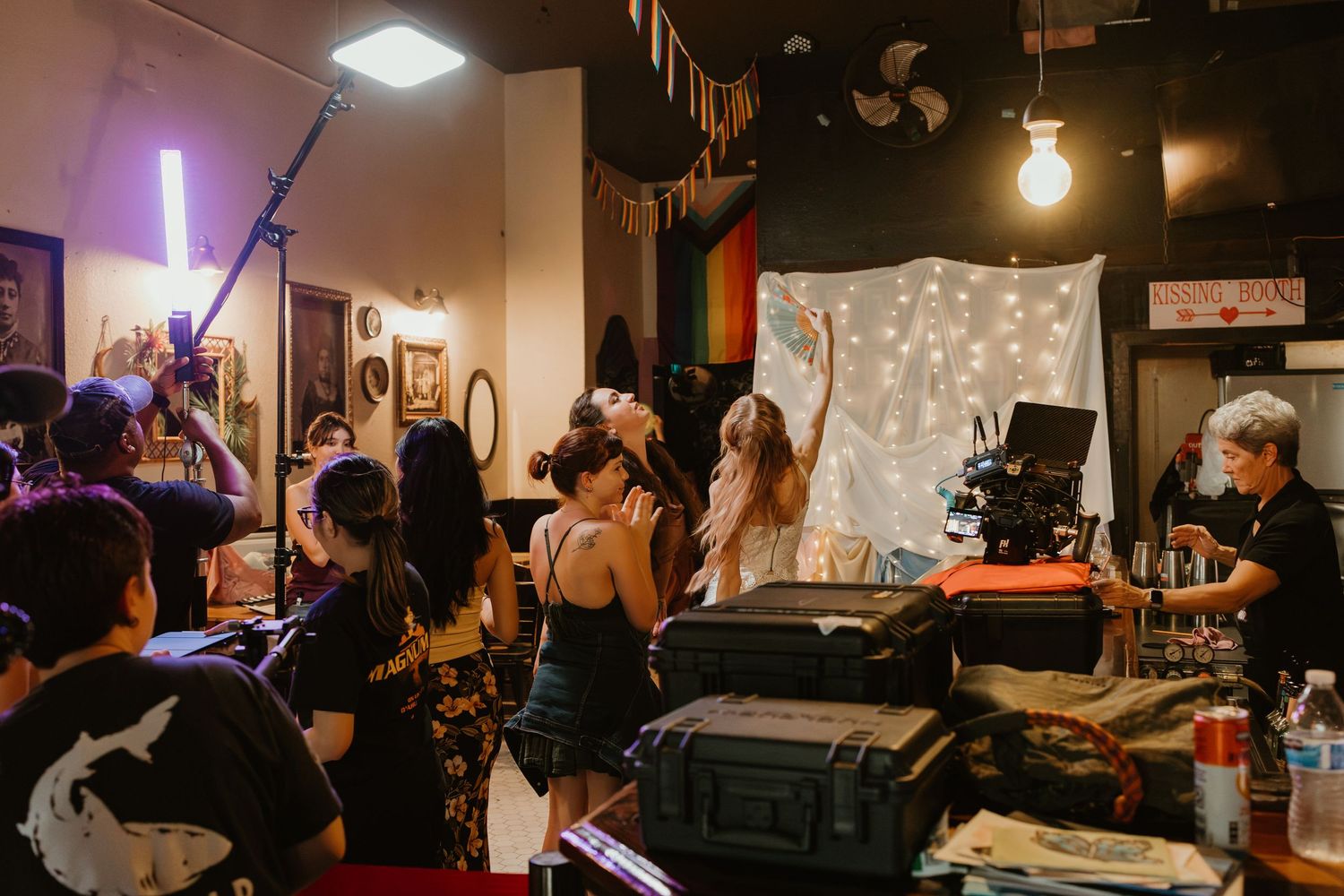 Film crew and participants gather in a decorated studio space during a video production shoot.
