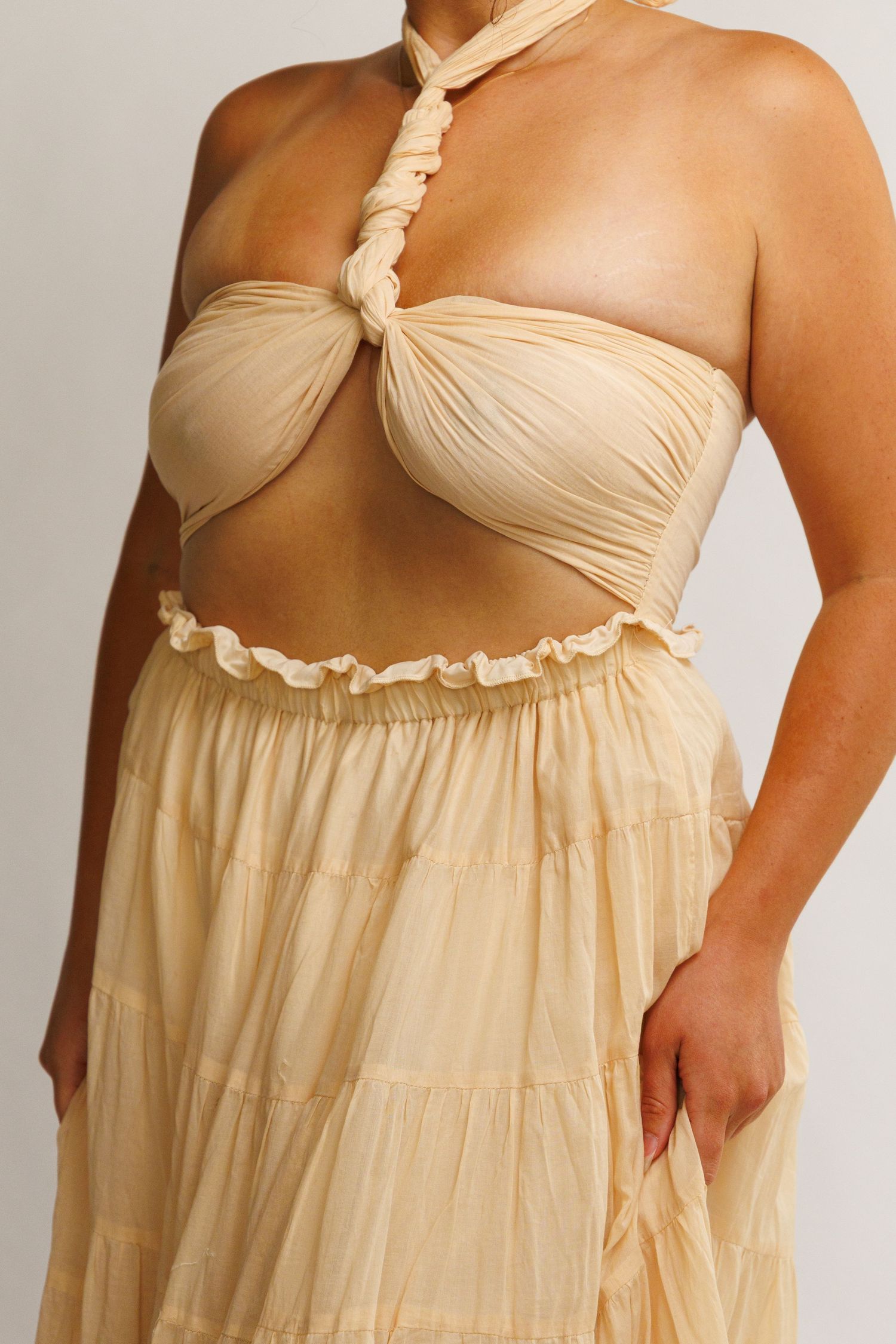 Cream halter crop top with ruched detail paired with a flowing tiered maxi skirt in matching beige tone.