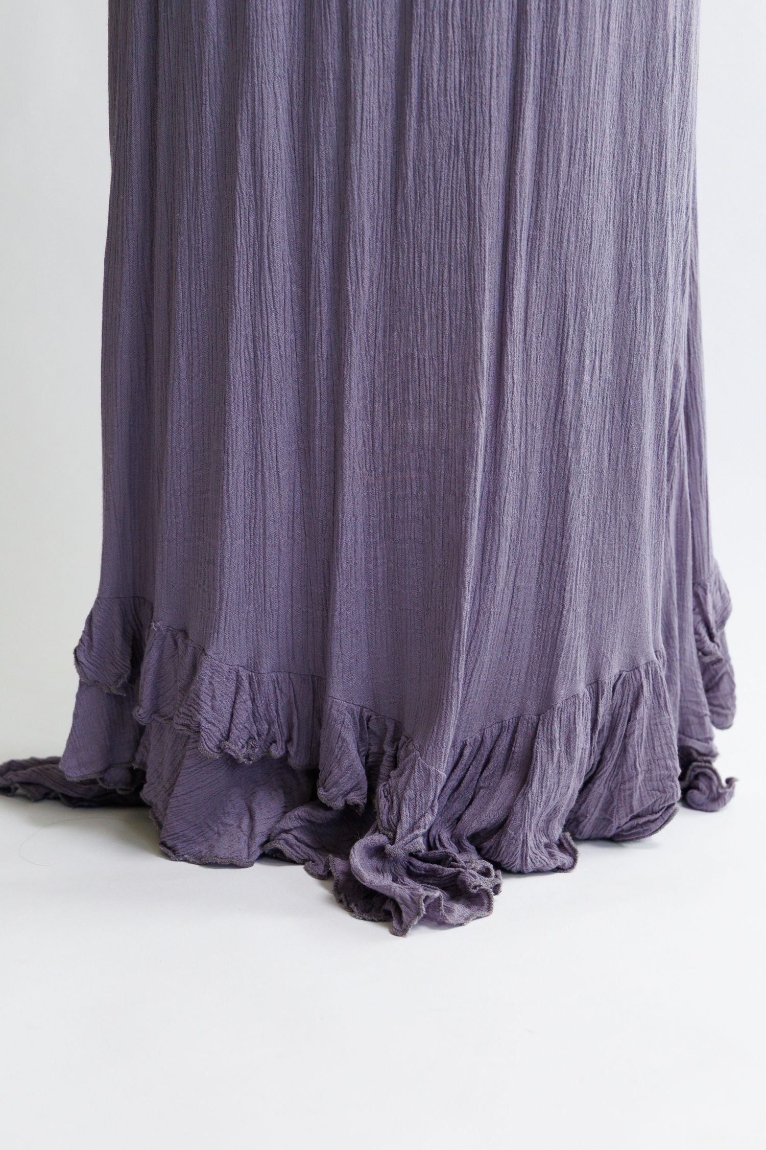 Purple crinkle fabric maxi skirt with ruffled hem detail, flowing silhouette in dusty violet hue.