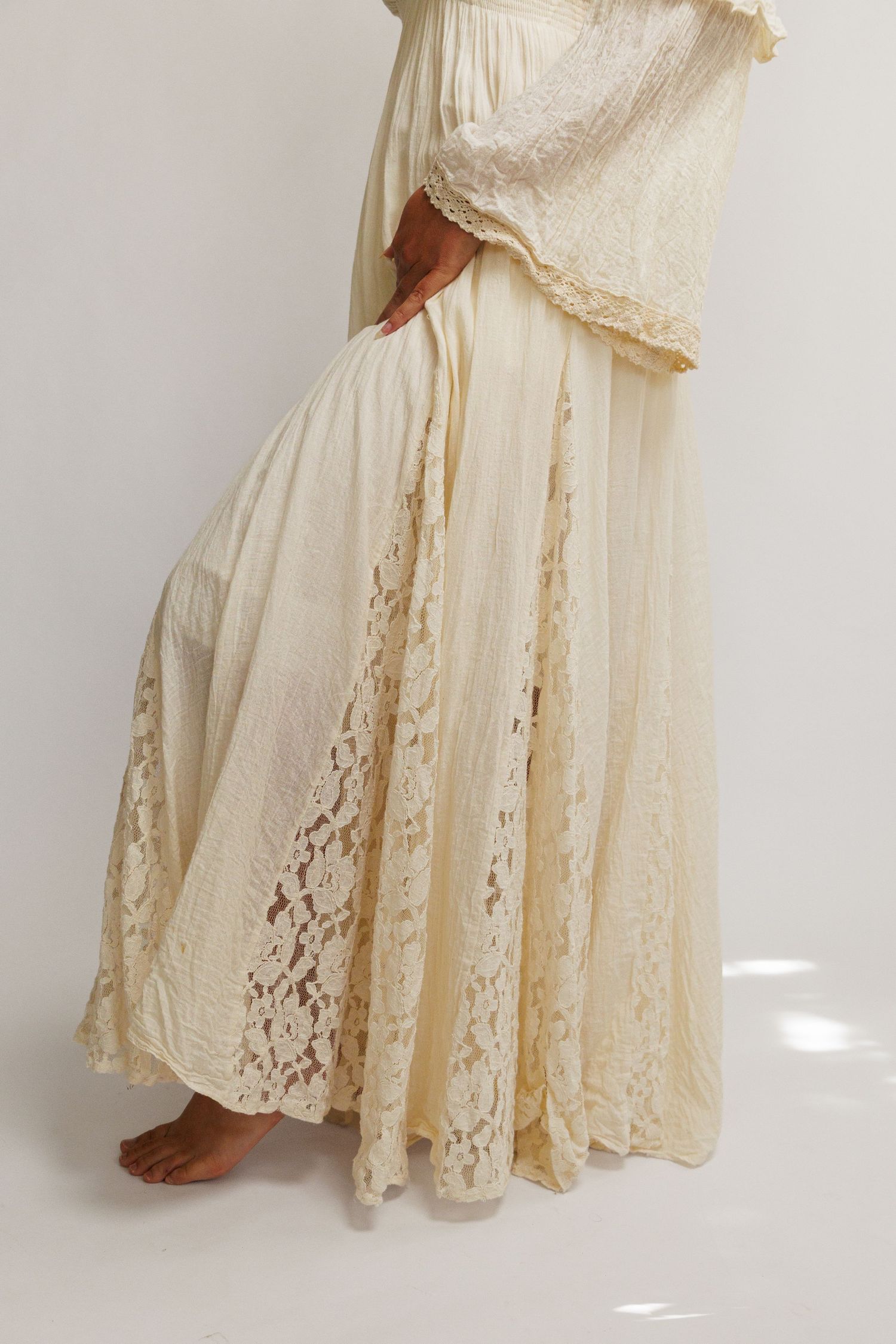 Cream lace maxi skirt with flowy silhouette, paired with matching ruffled top, worn by barefoot model.