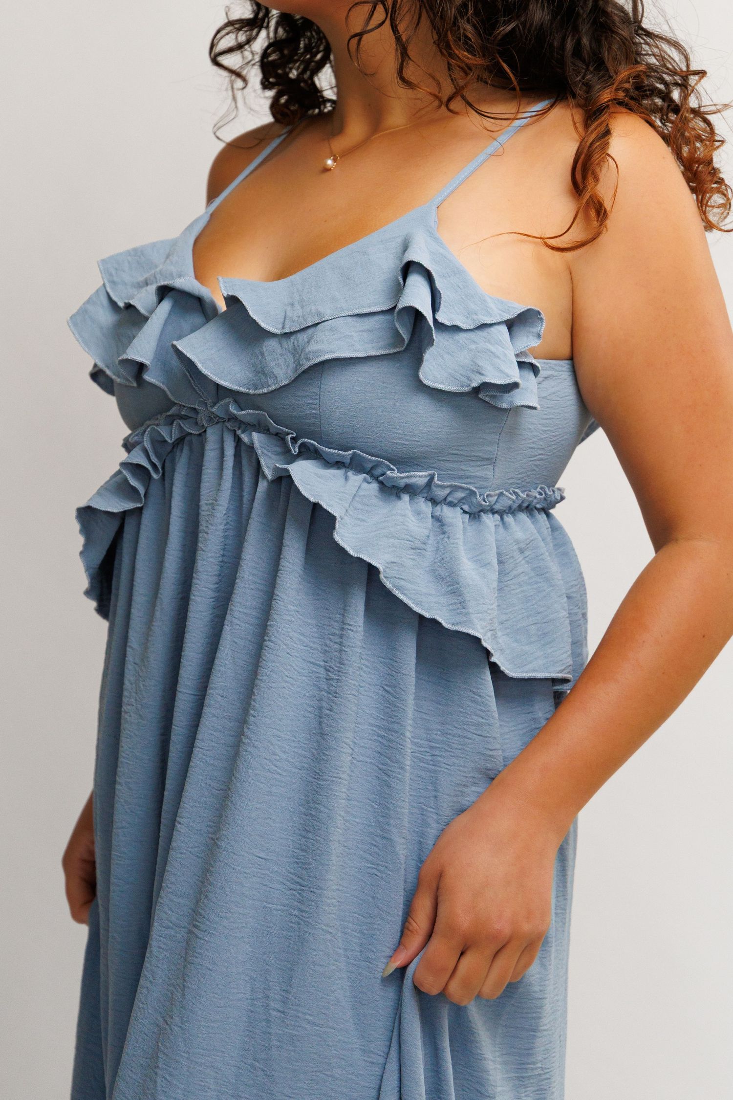Blue ruffle maxi dress with spaghetti straps and smocked waist detail on a plus-size model.