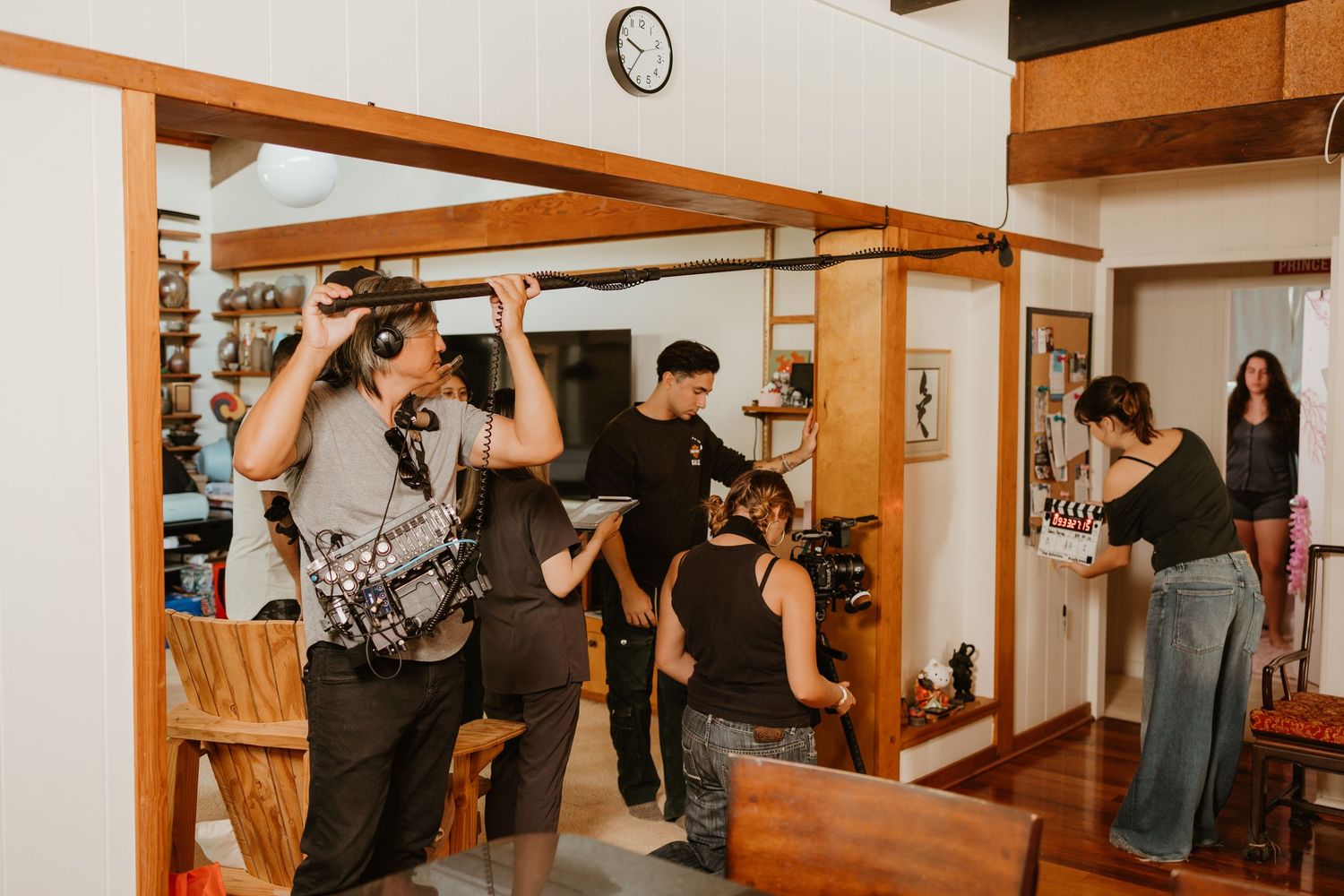 People socializing in a cozy indoor space with wooden decor, mirrors, and a wall clock in the background.