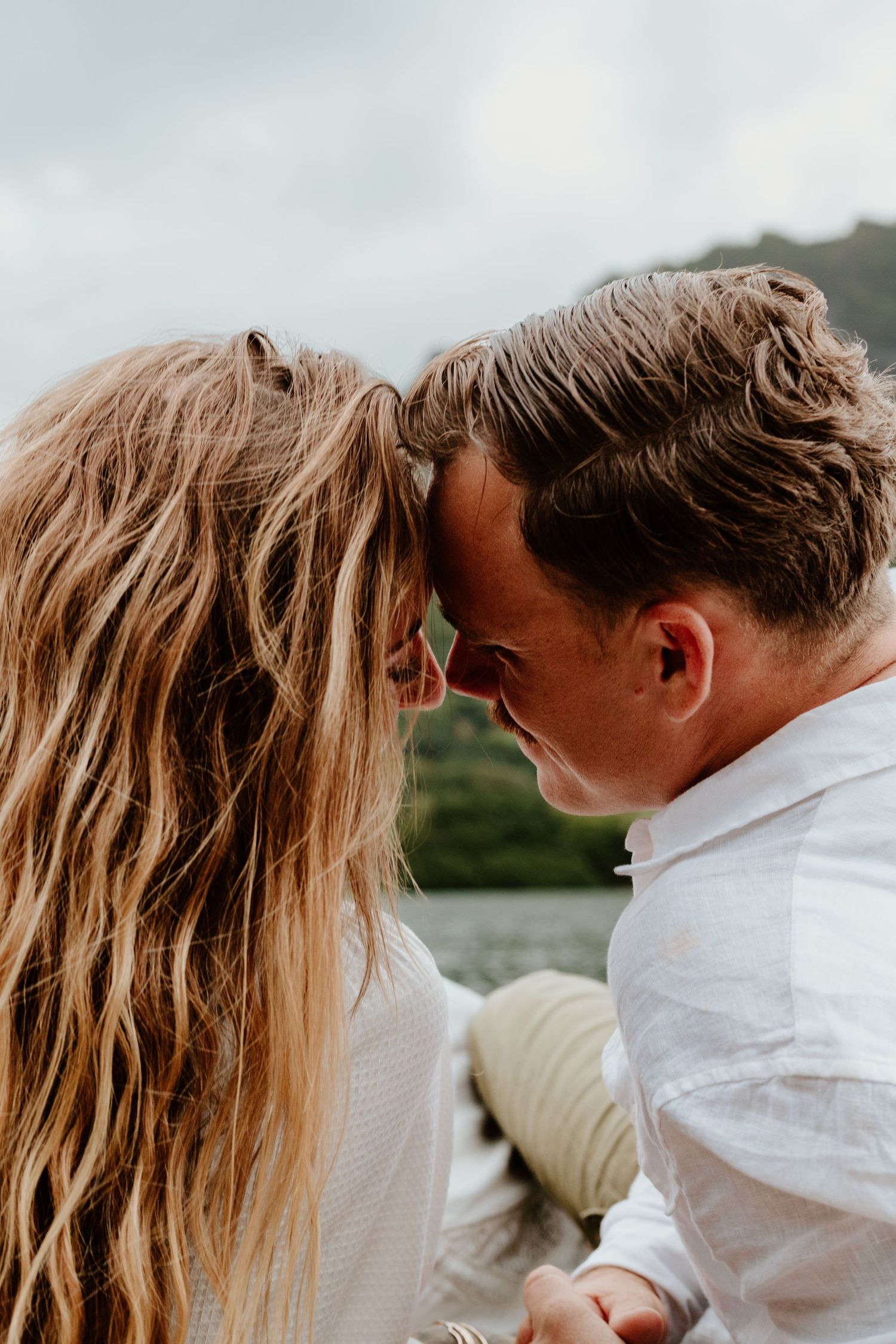 Couple touching foreheads intimately with a scenic mountain backdrop.