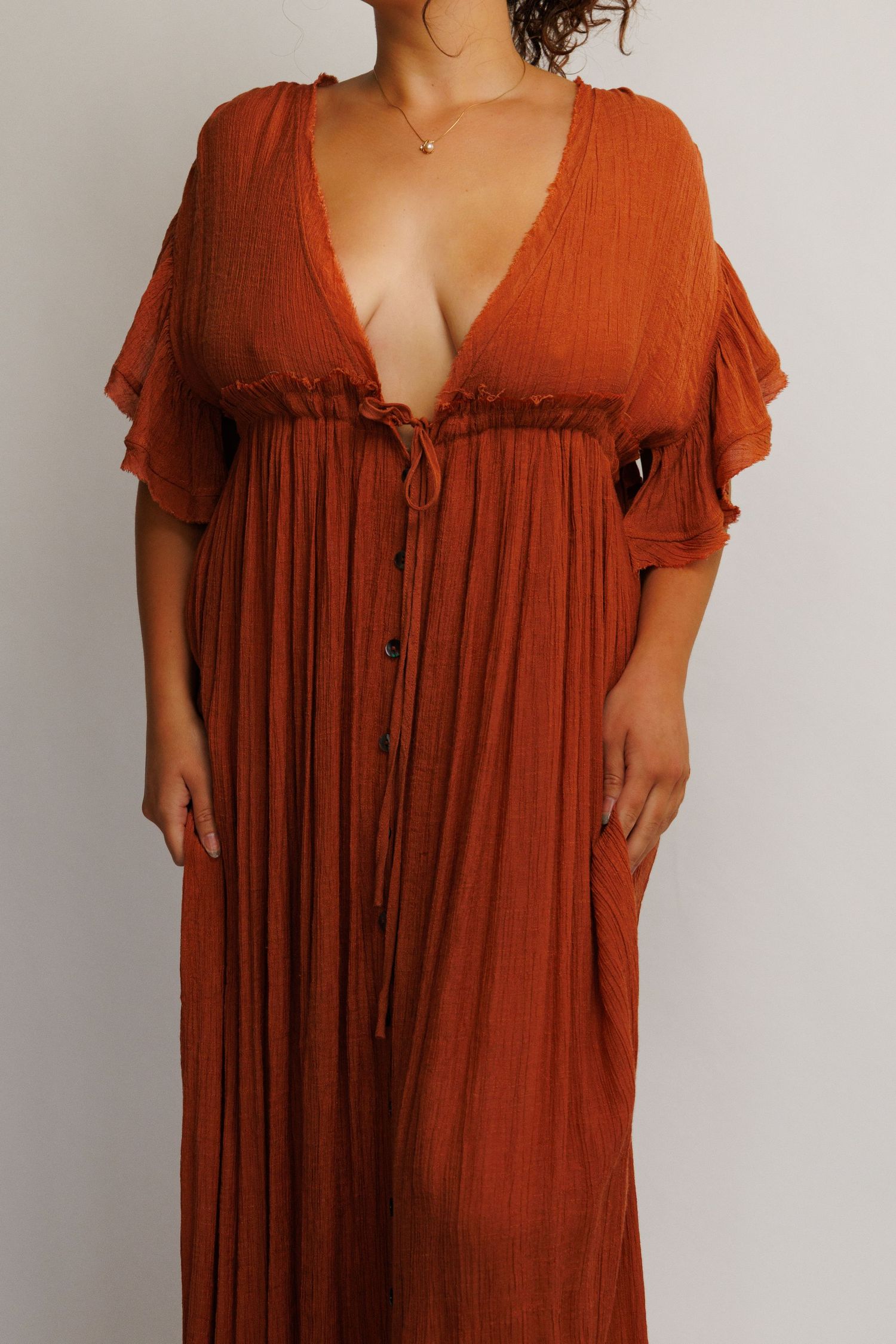 Rust orange maxi dress with deep V-neckline, flutter sleeves, smocked waist, and button-front detail.