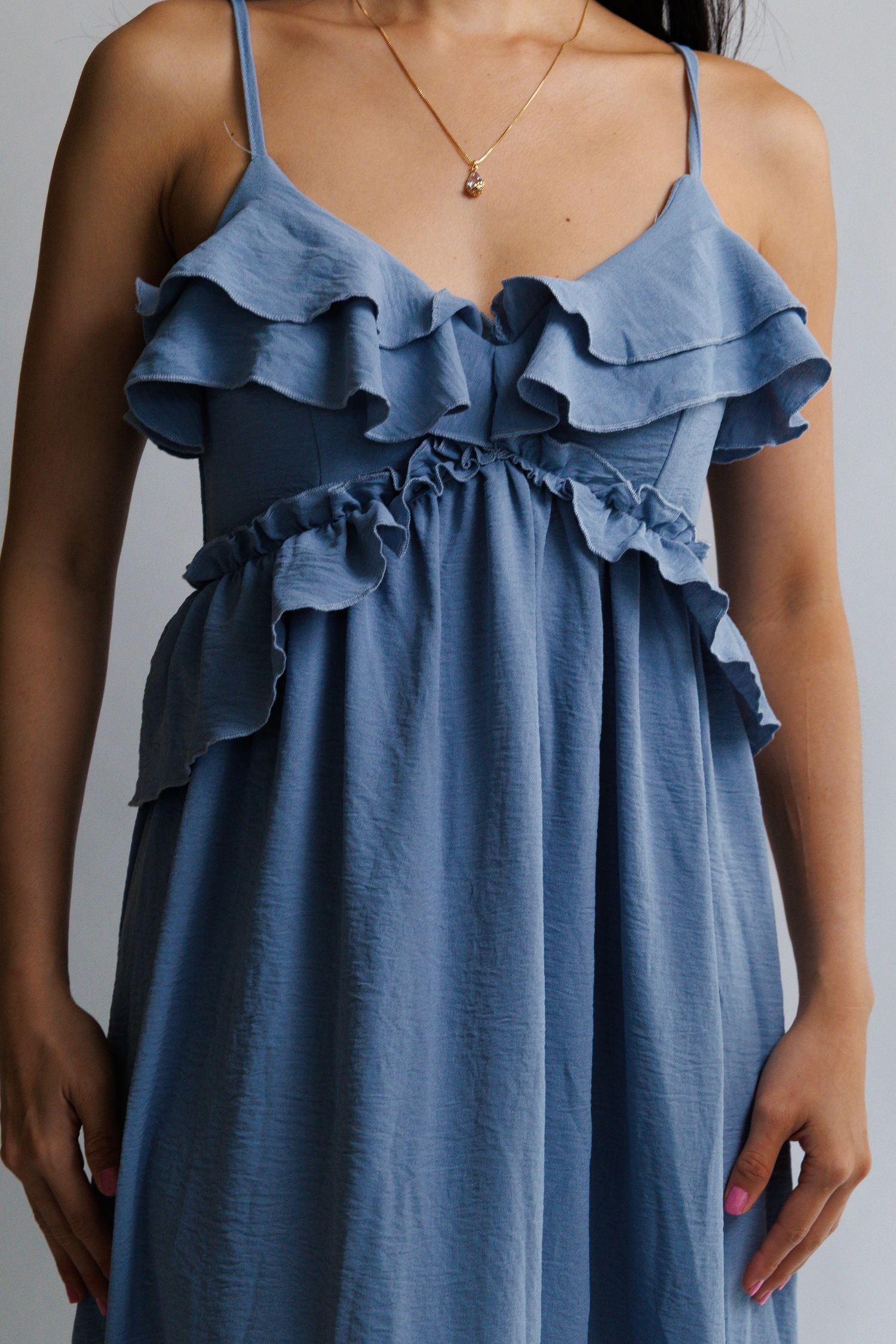 Blue ruffle midi dress with spaghetti straps and tiered ruffle bodice detail, worn with a delicate gold necklace.