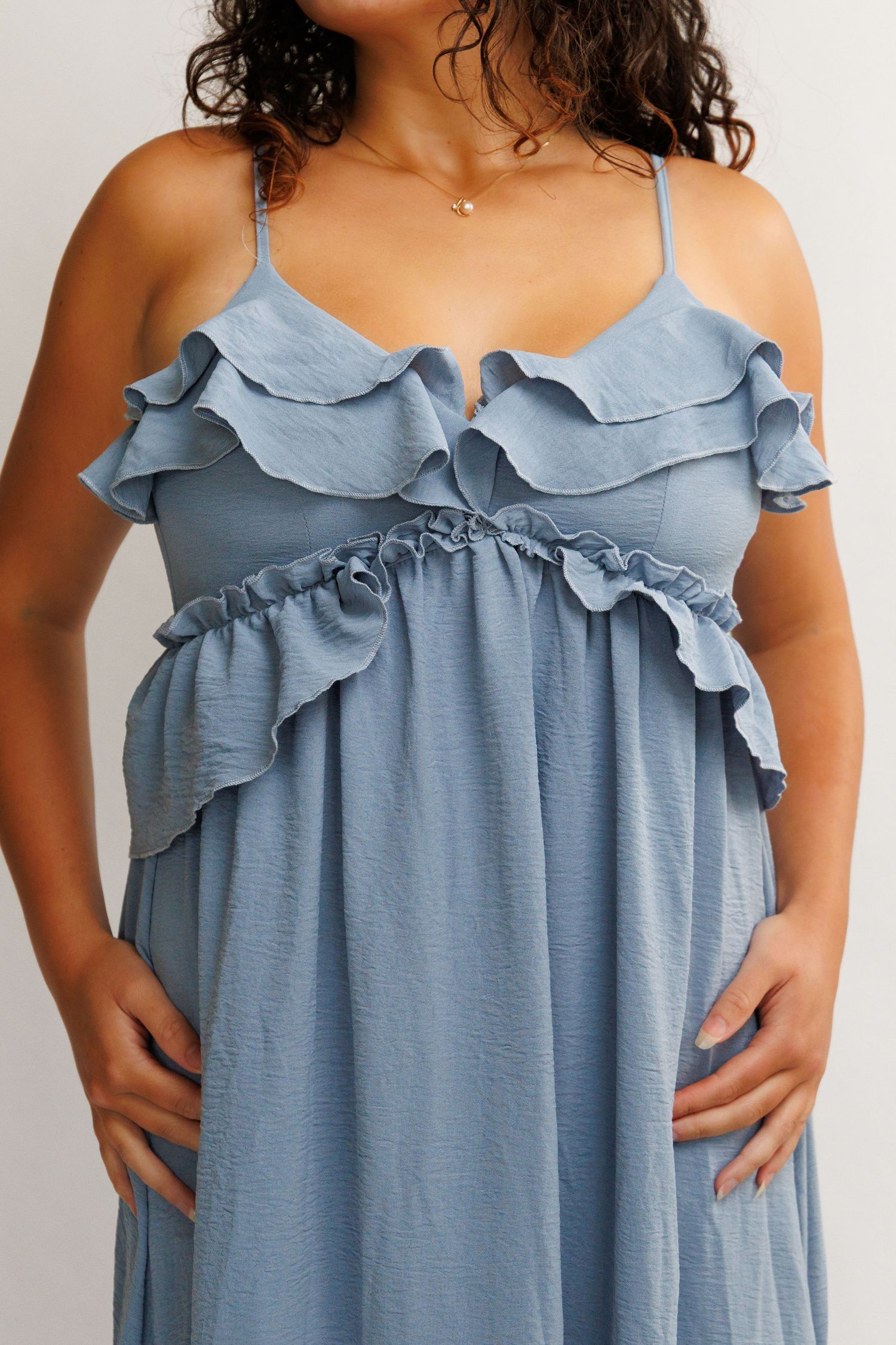 Blue ruffle maternity maxi dress with spaghetti straps and empire waist on pregnant model.