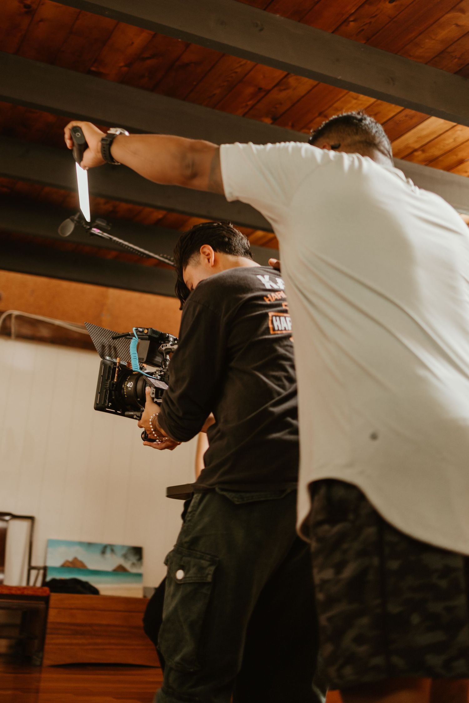 Two filmmakers operating a professional camera on an indoor video production shoot.