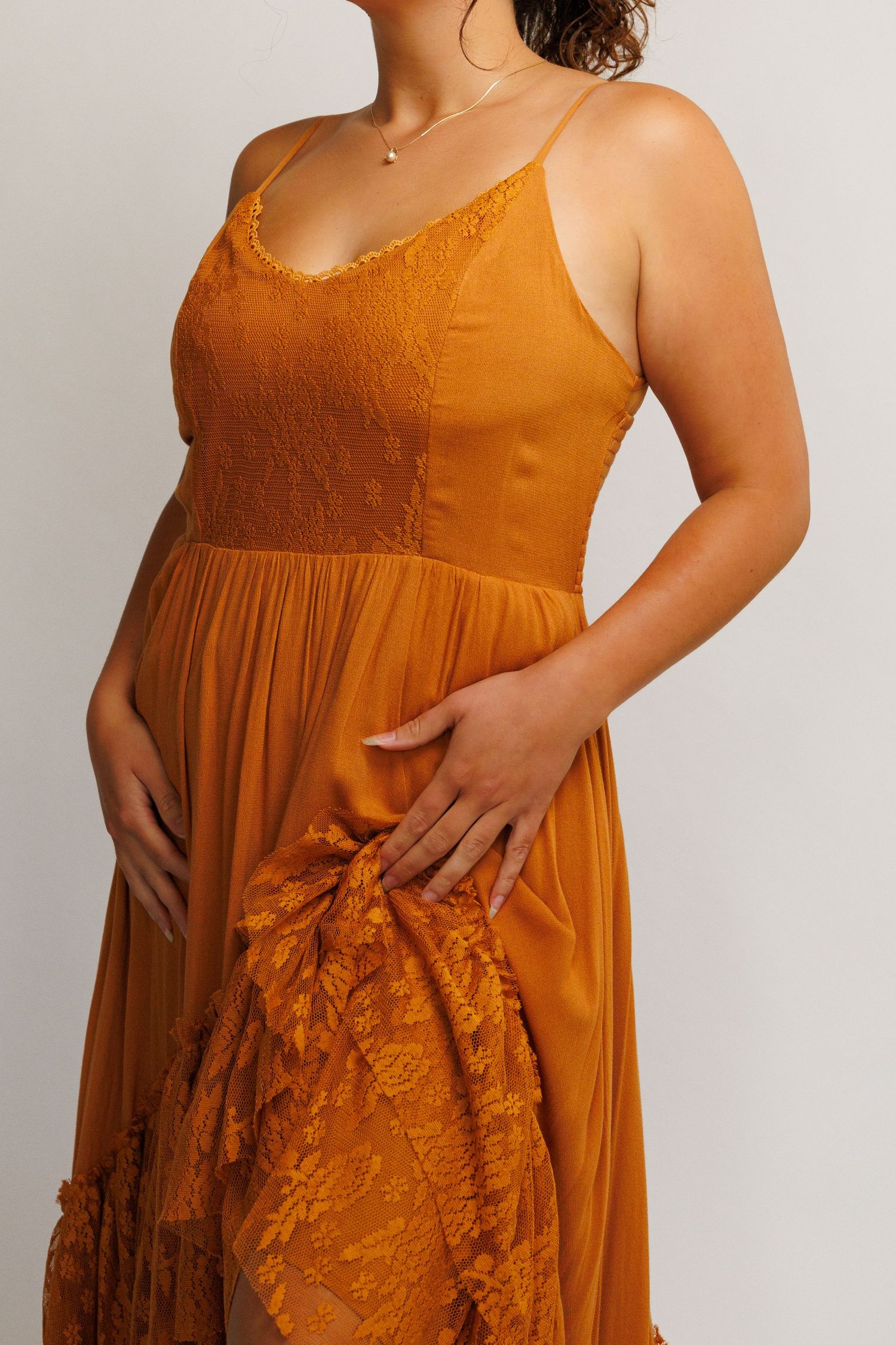 Woman wearing a mustard yellow lace and chiffon spaghetti strap maxi dress with floral lace details.