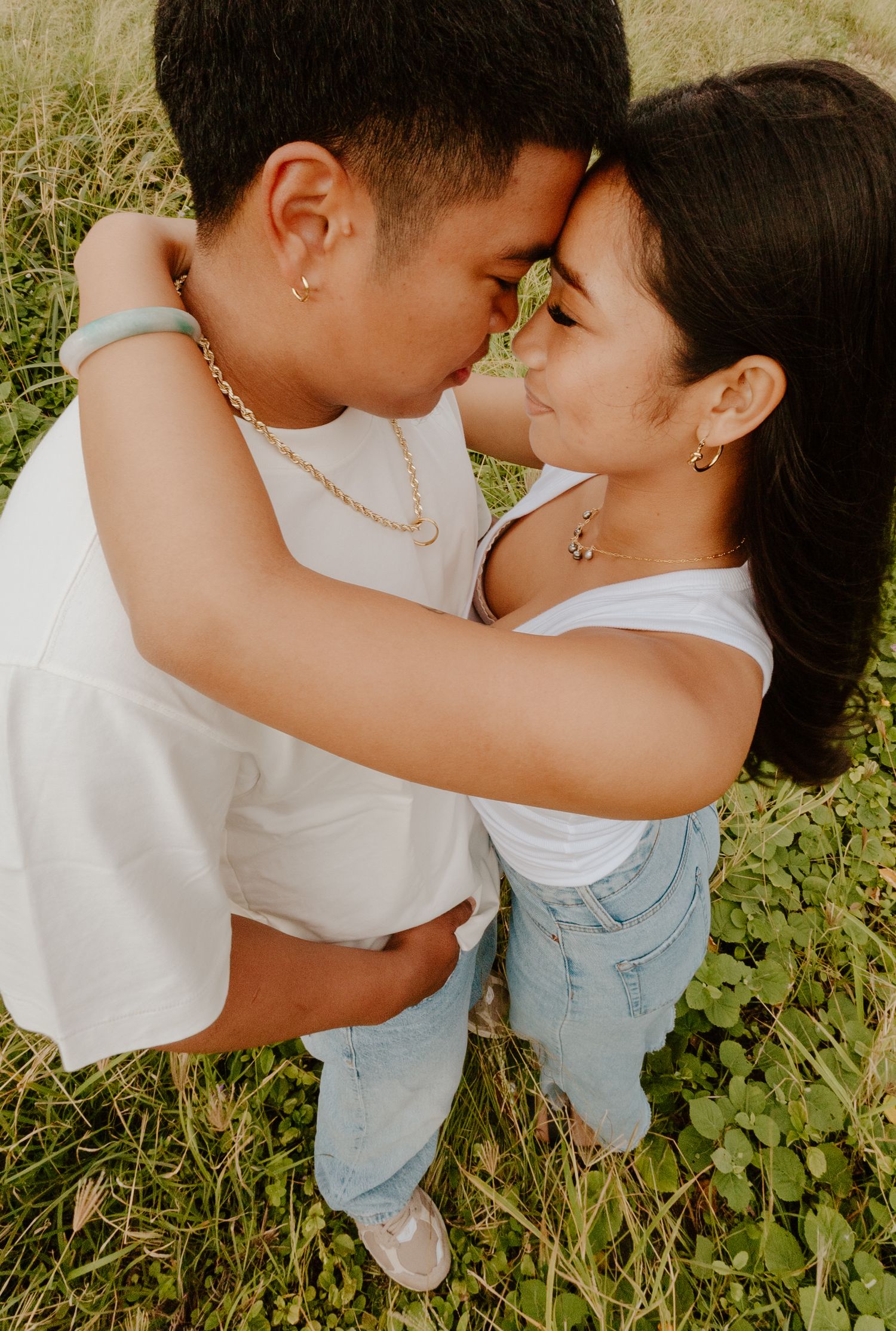 Young couple about to kiss while embracing in a green field.