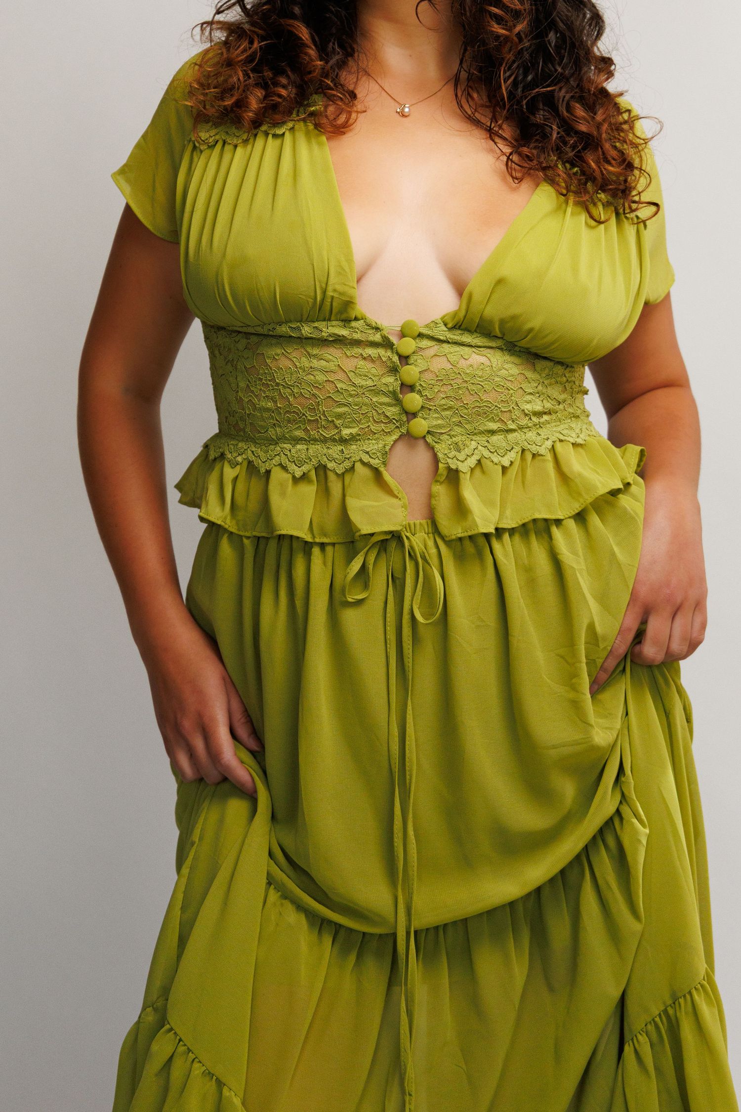 Woman wearing a chartreuse green lace crop top and matching maxi skirt set with ruffle details.