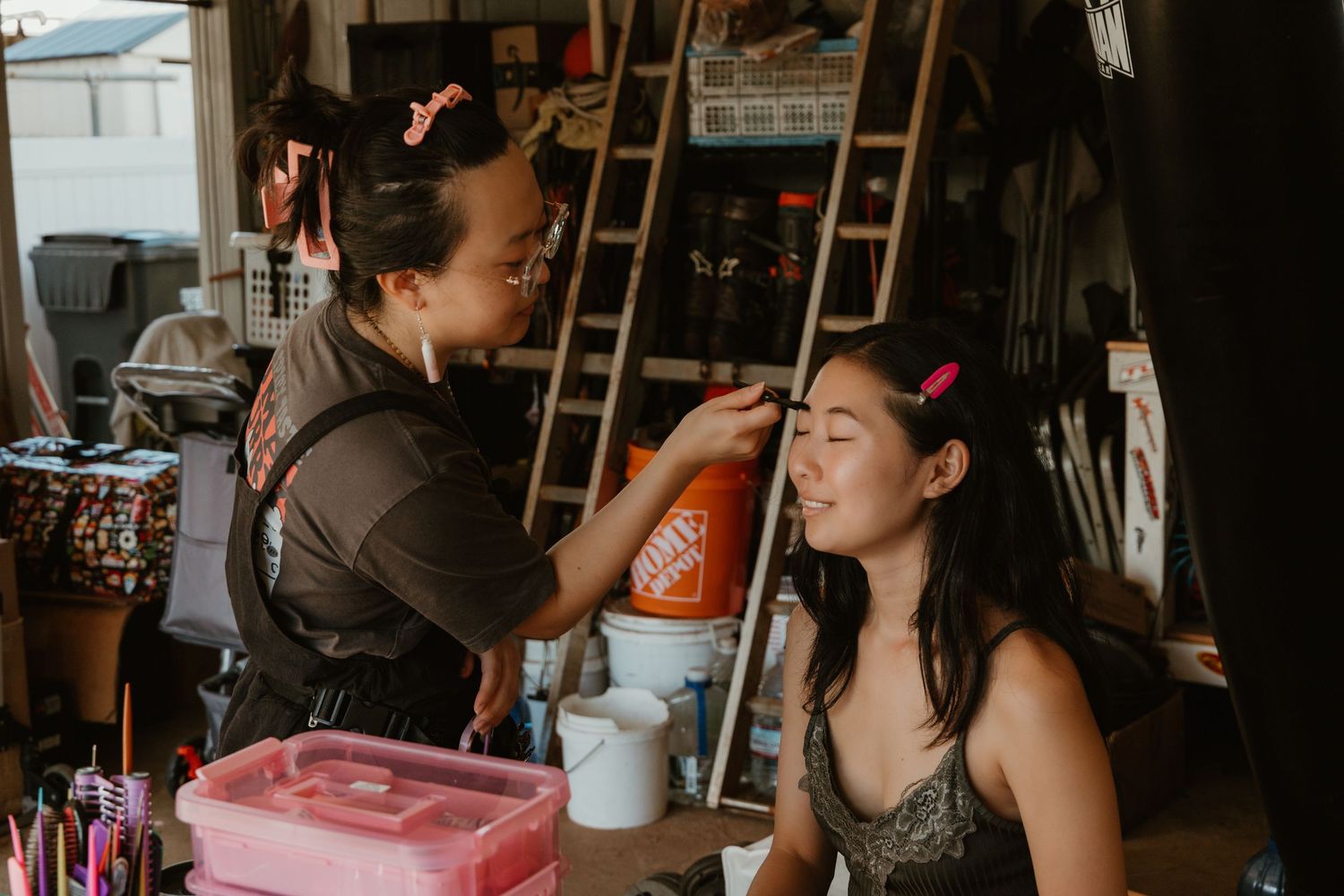 Makeup artist applying cosmetics to young woman in a workshop studio setting.