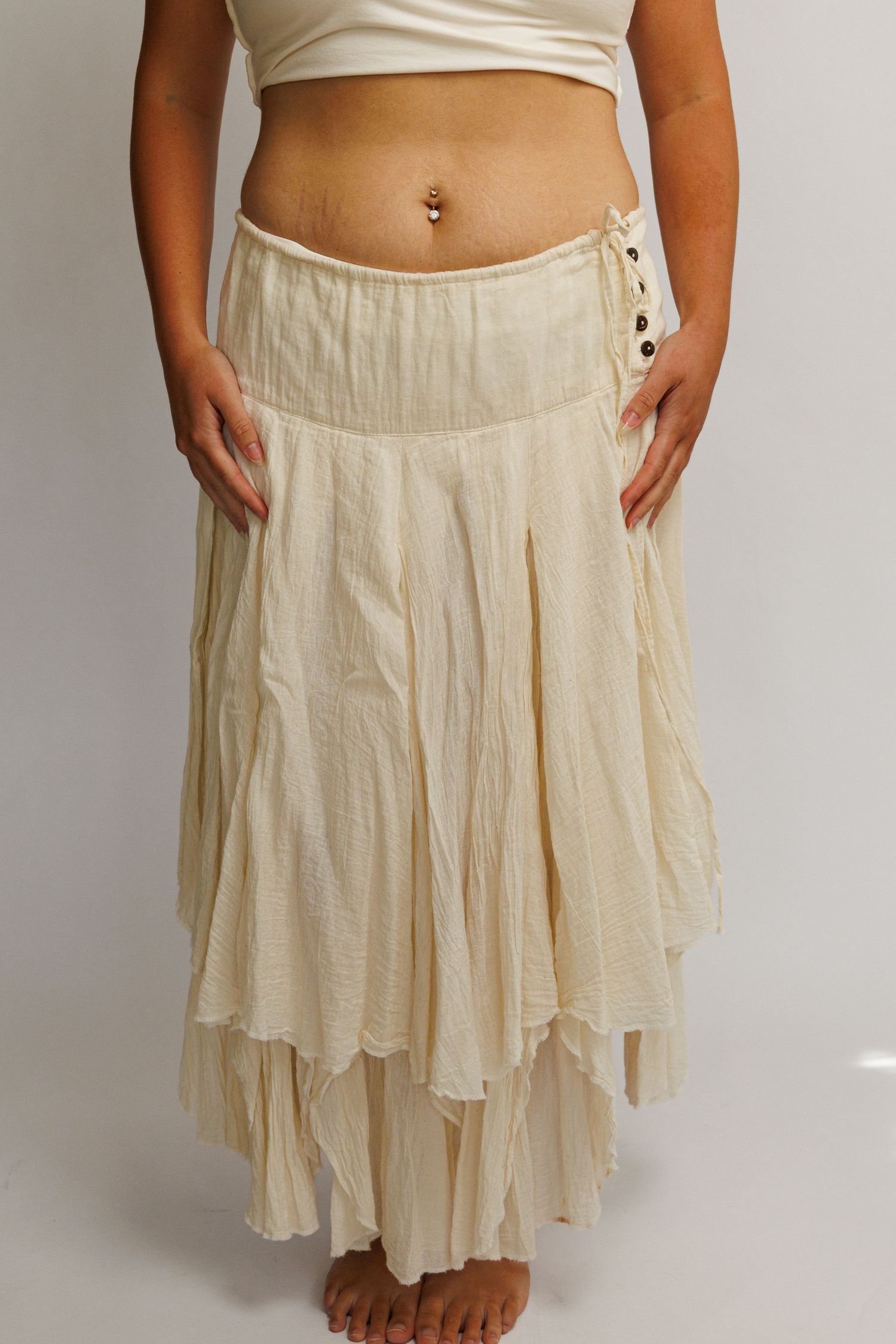 Cream layered boho maxi skirt with ruffled hem and side buttons, paired with a white crop top.