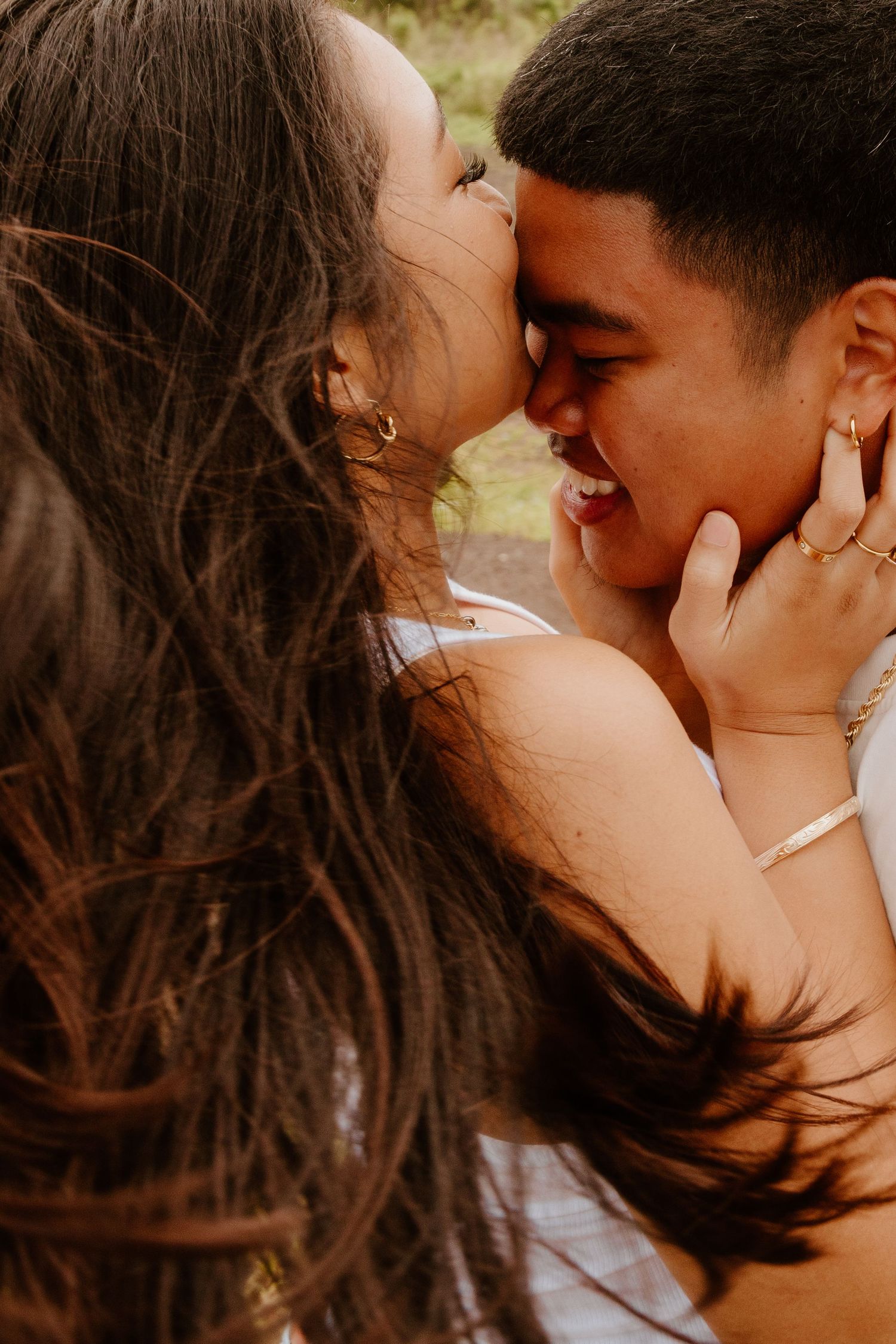 A close-up of a couple sharing a tender, laughing kiss surrounded by warm golden light.