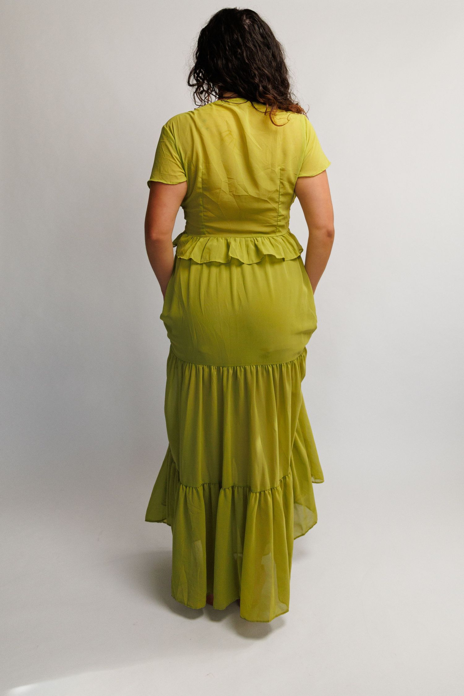 Woman wearing a chartreuse green tiered ruffle maxi skirt and matching short sleeve top, back view.