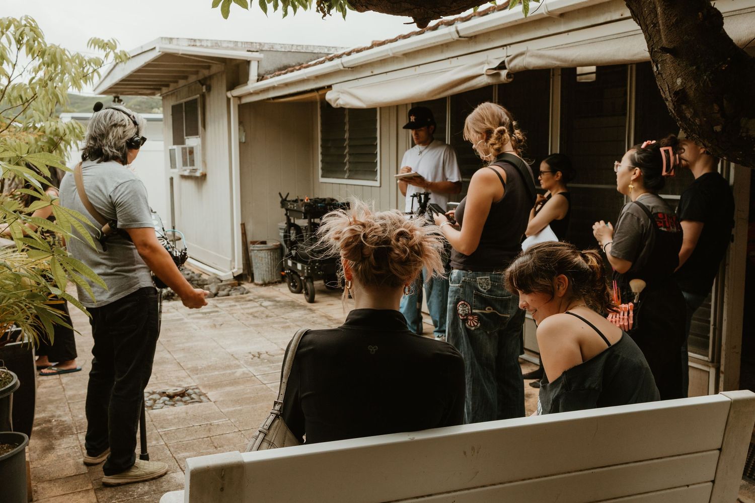 Group of people gathered in backyard listening to director during outdoor film production shoot.