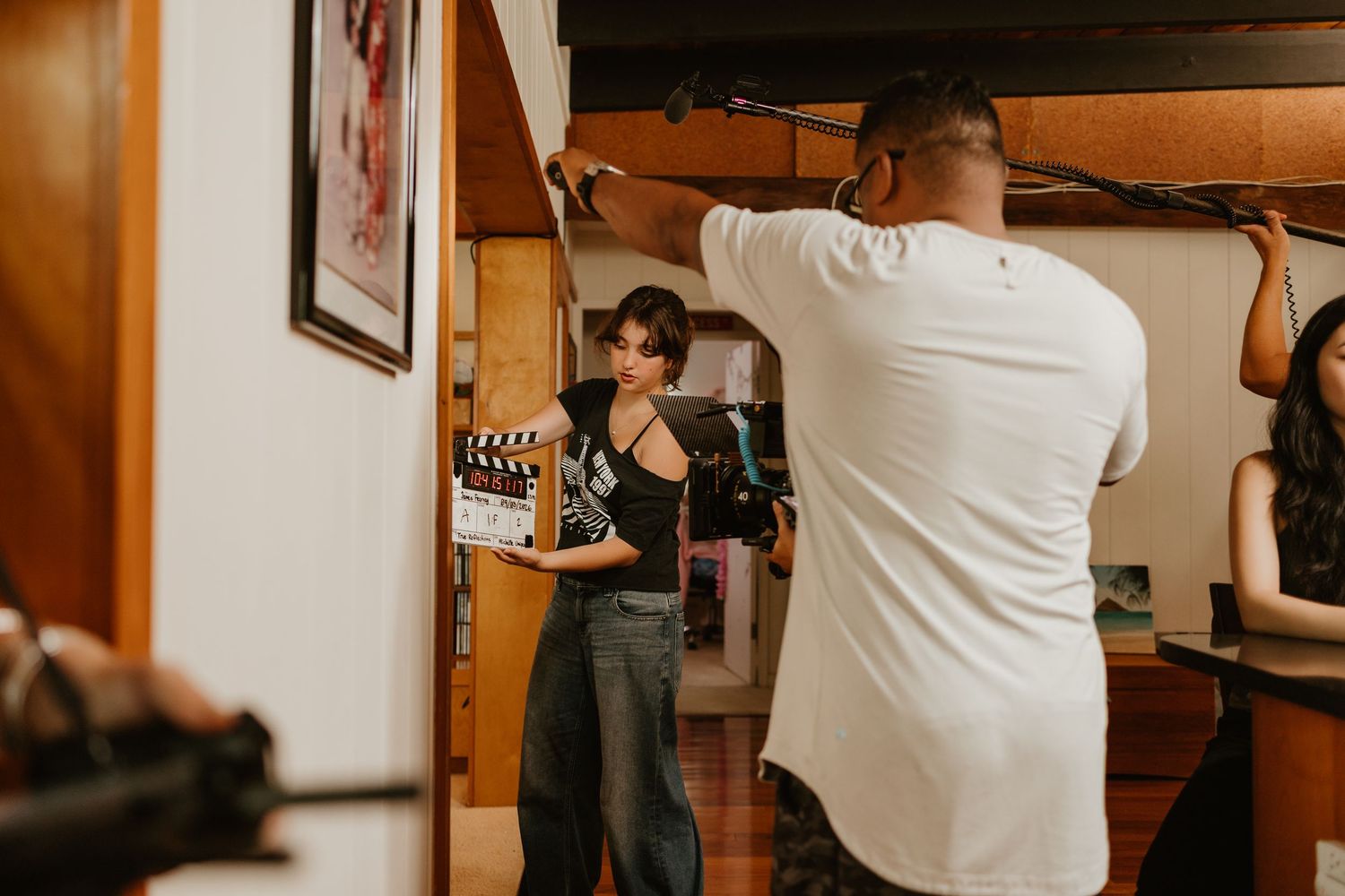 Behind-the-scenes film production with crew member holding clapperboard on an indoor movie set.