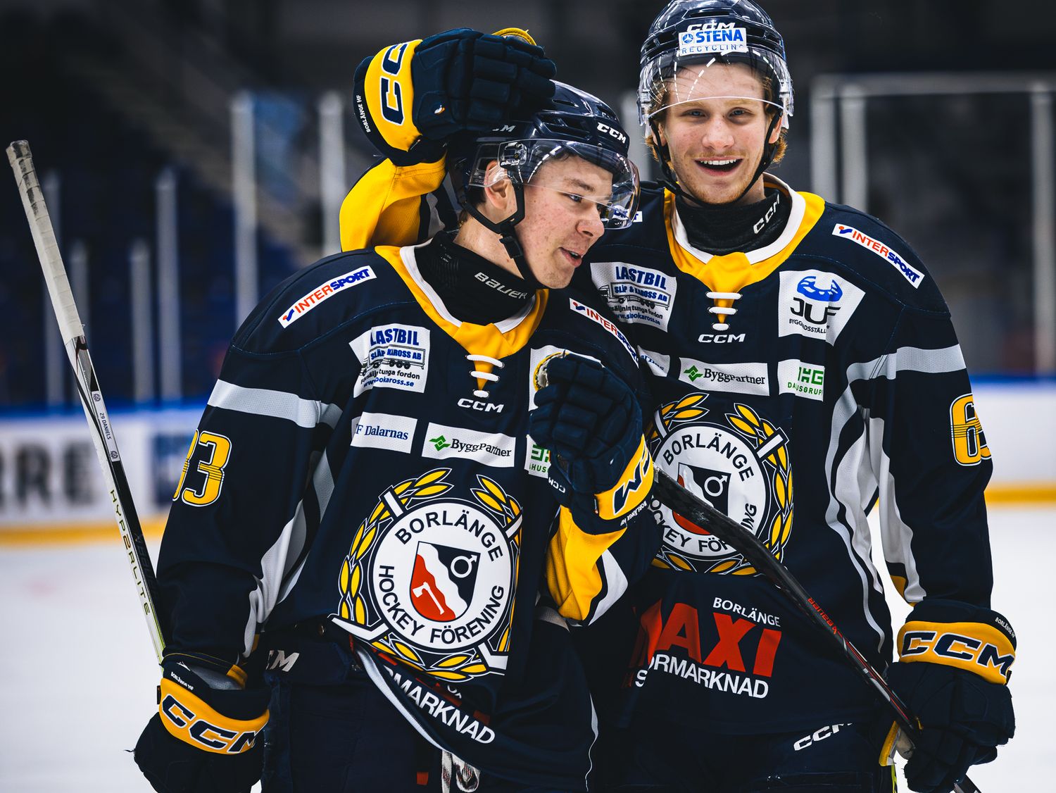 Hockey team members in black and yellow jerseys during competitive match.