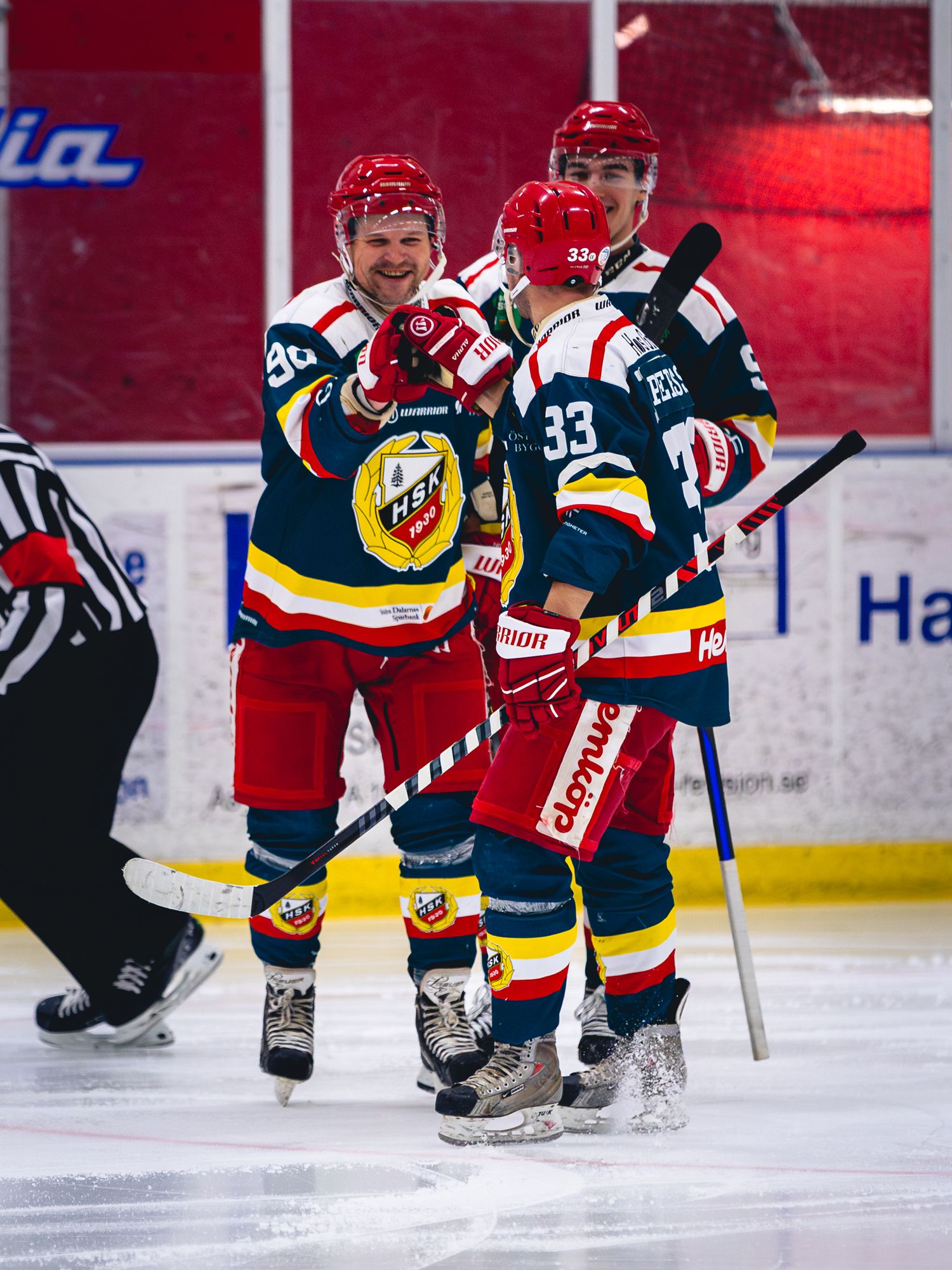 Ice hockey players in red and dark uniforms compete during match.
