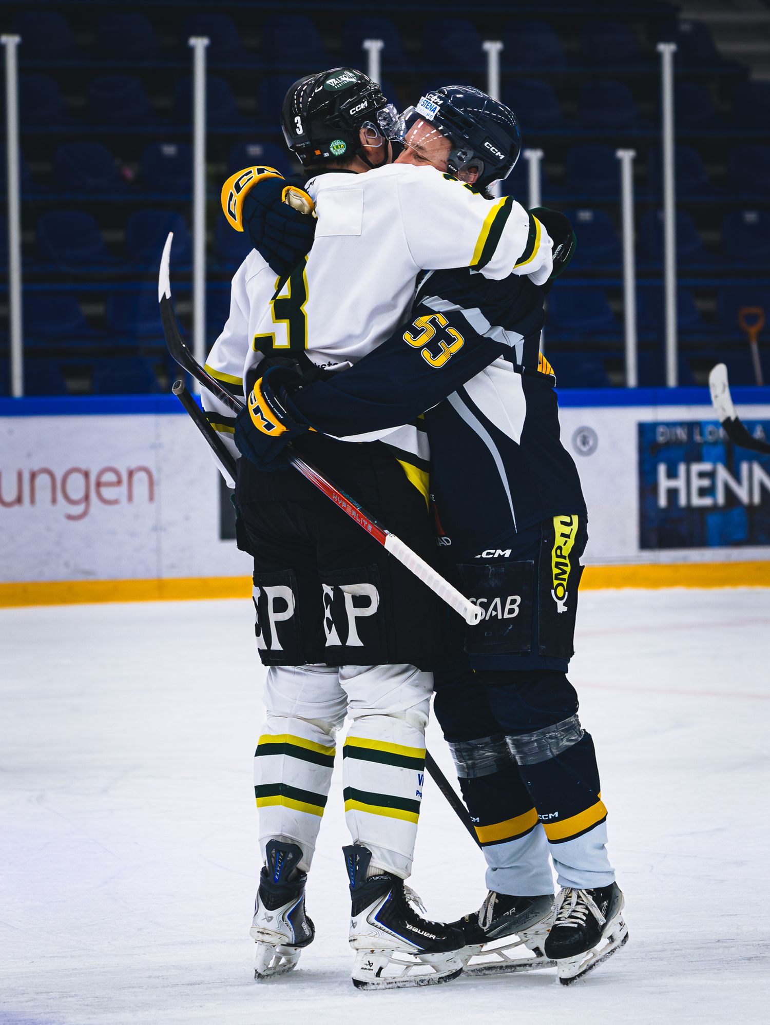 Hockey players in black and yellow uniforms engaged in gameplay on the ice.