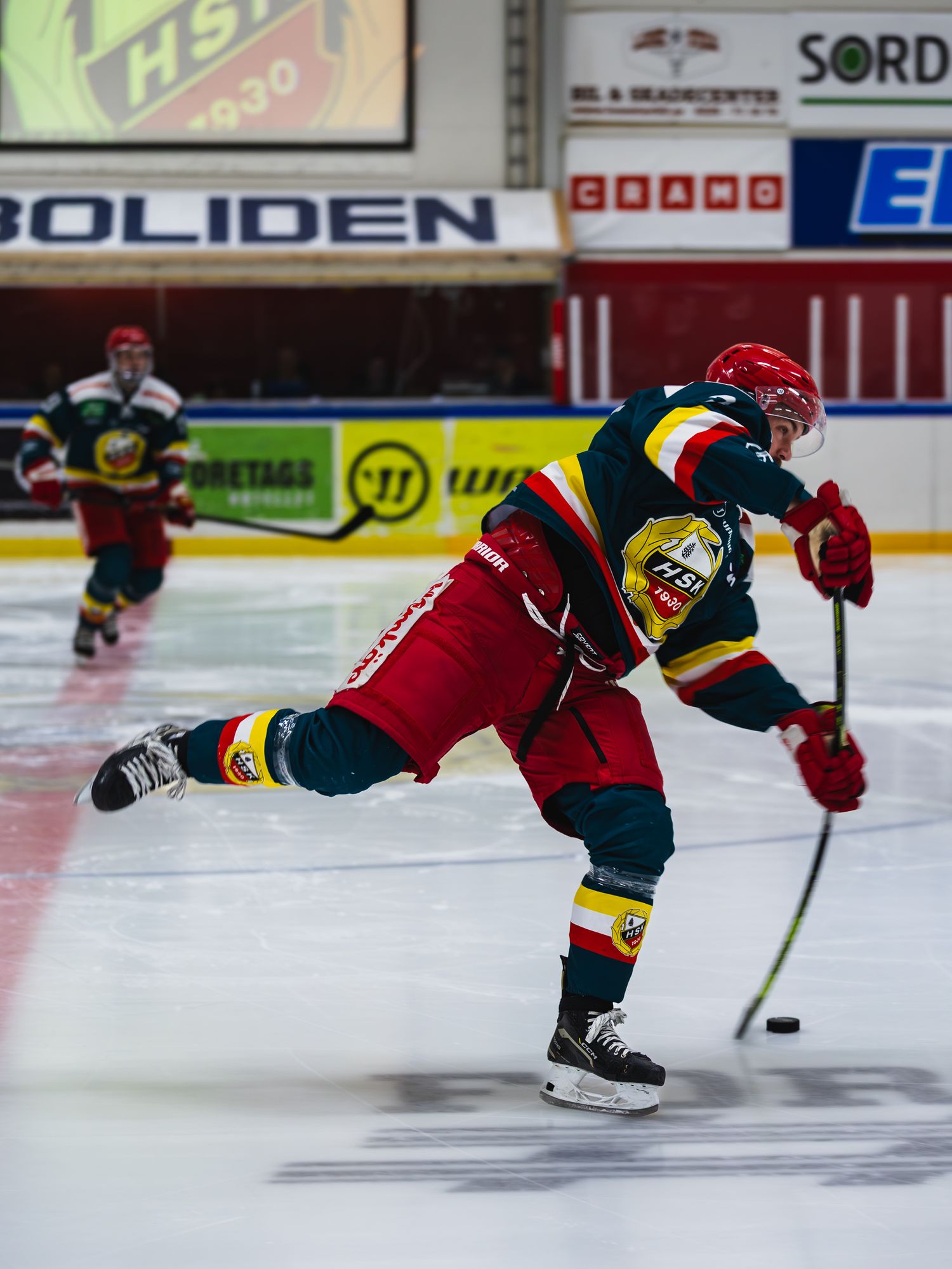 Hockey player in red uniform makes a diving play on the ice.