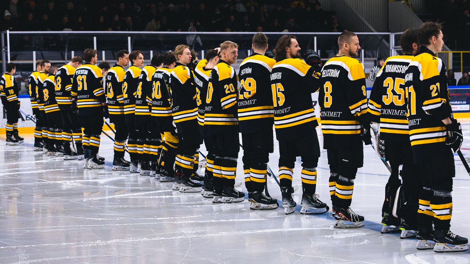 Hockey players lined up on ice in black and yellow uniforms before game start.