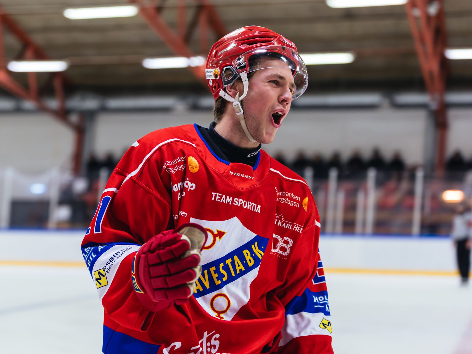 Hockey players in red jerseys celebrating during a competitive match.