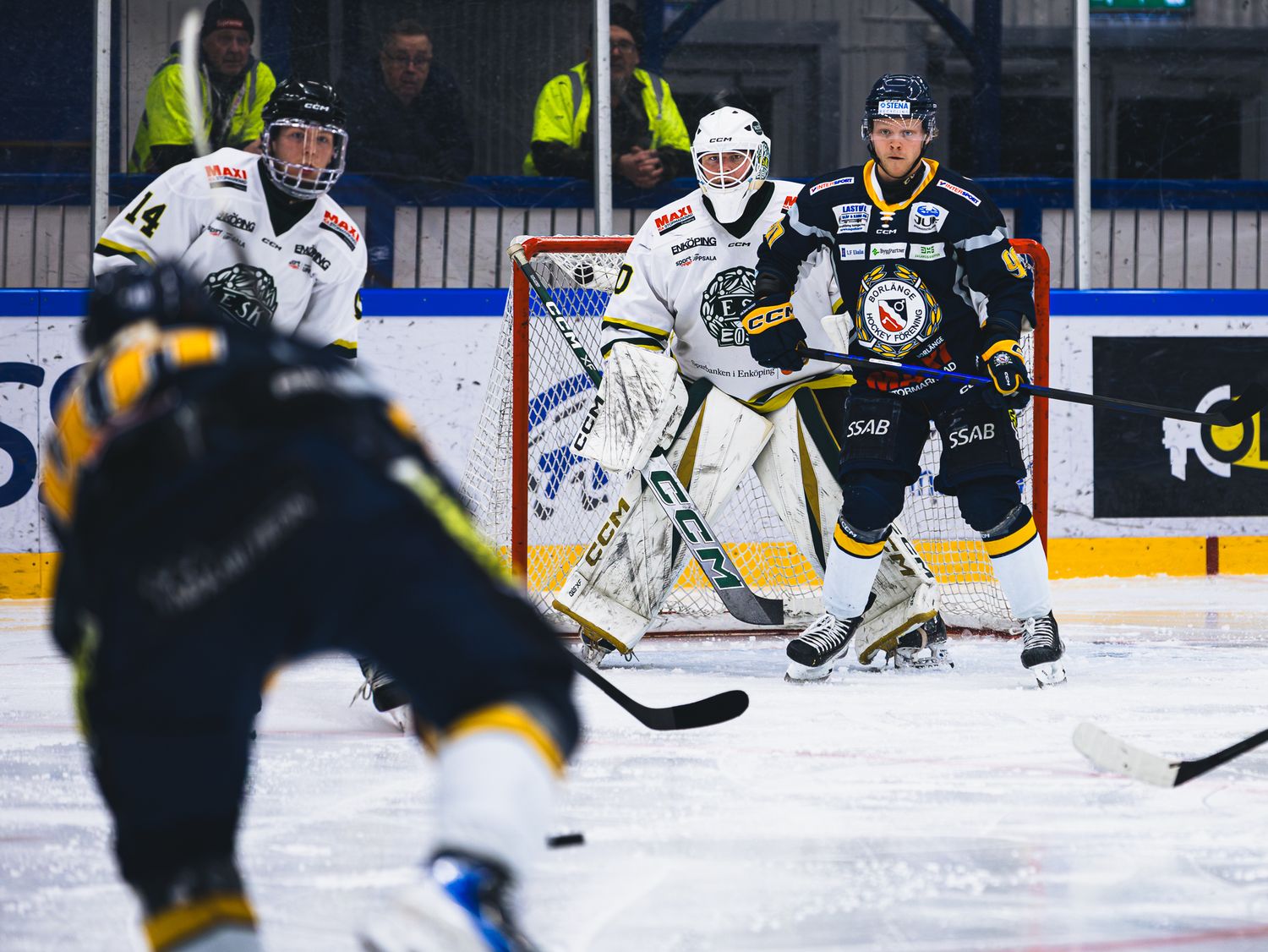 Hockey players from opposing teams battle for puck control during fast-paced match.