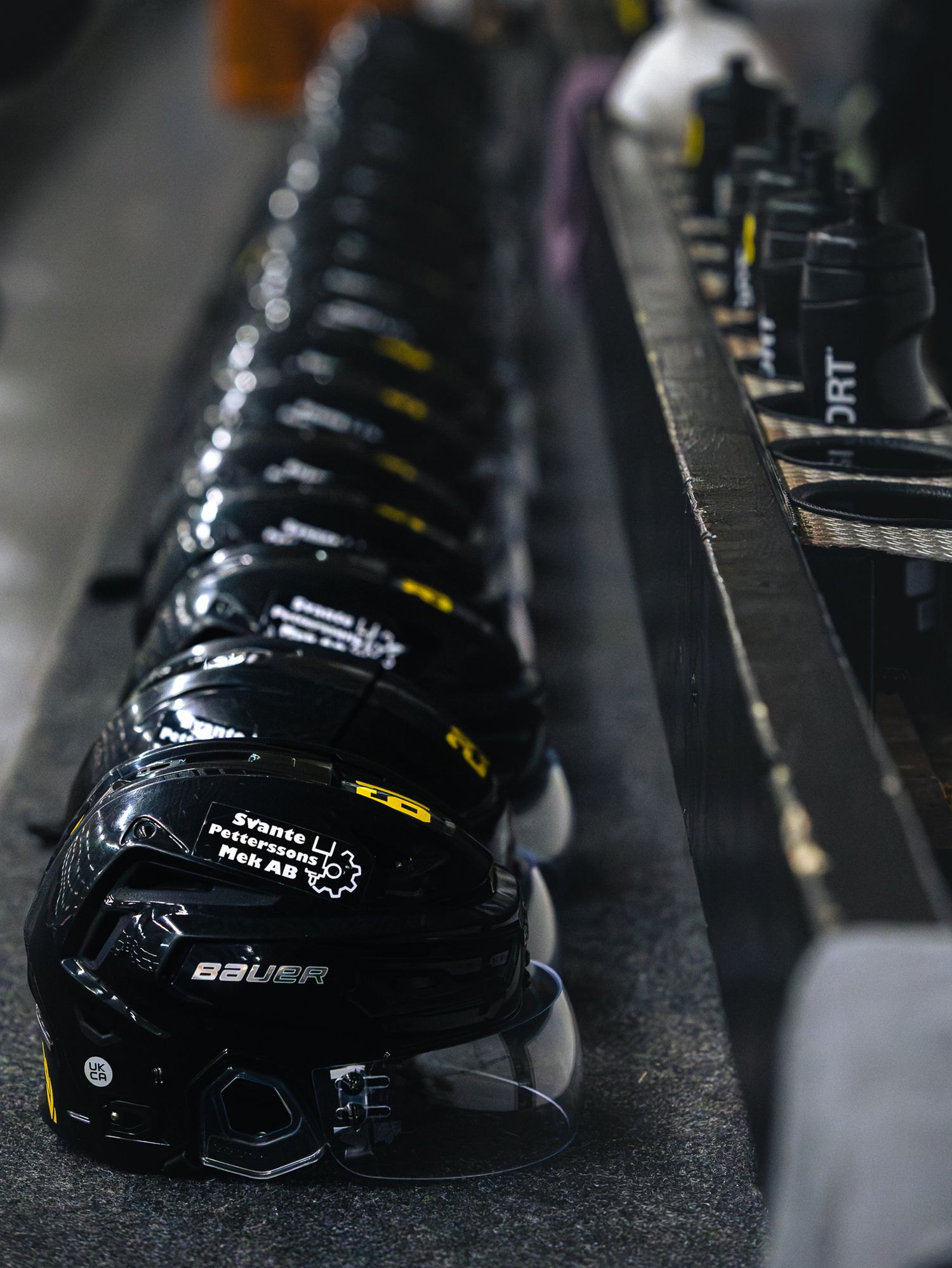Close-up view of black hockey skates lined up in a row showing detailed boot construction.