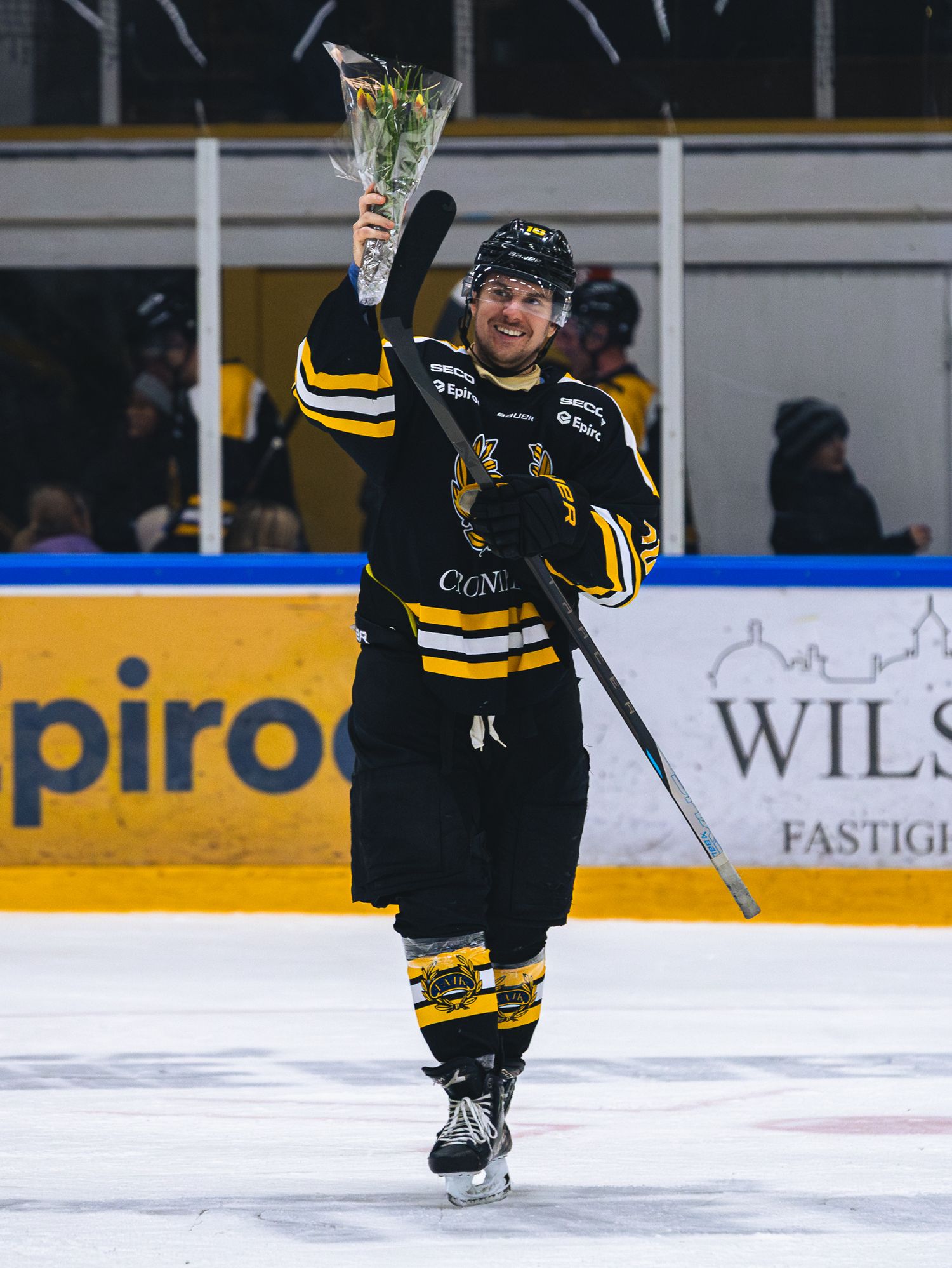 Hockey players in black and yellow uniforms skating on ice during game action.