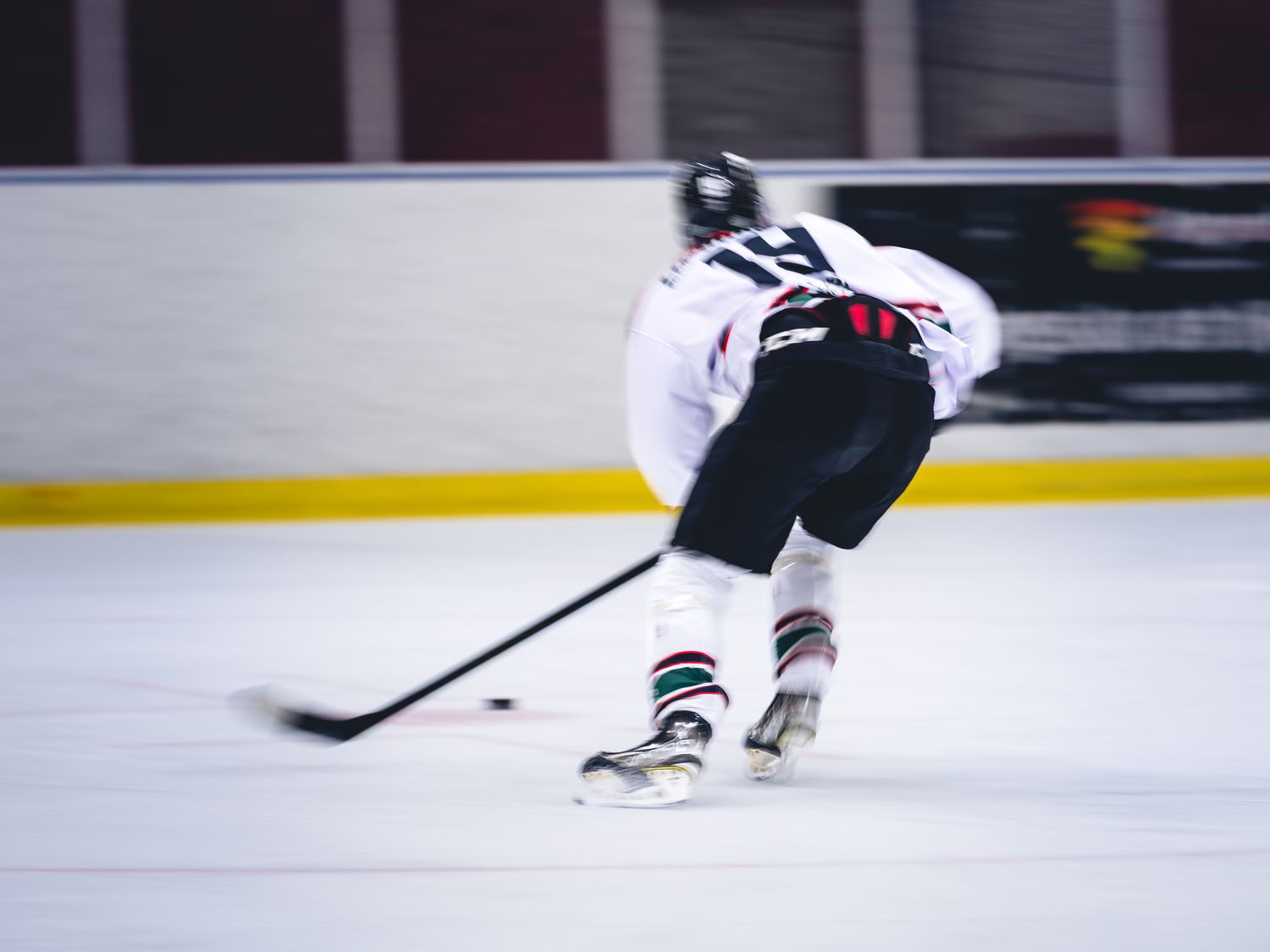 Hockey players skate across the ice rink during competitive gameplay.