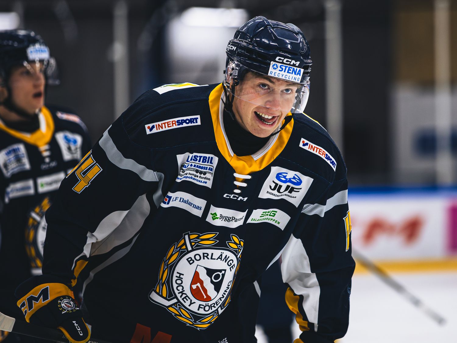 Ice hockey players in black and yellow uniforms compete during an intense game.