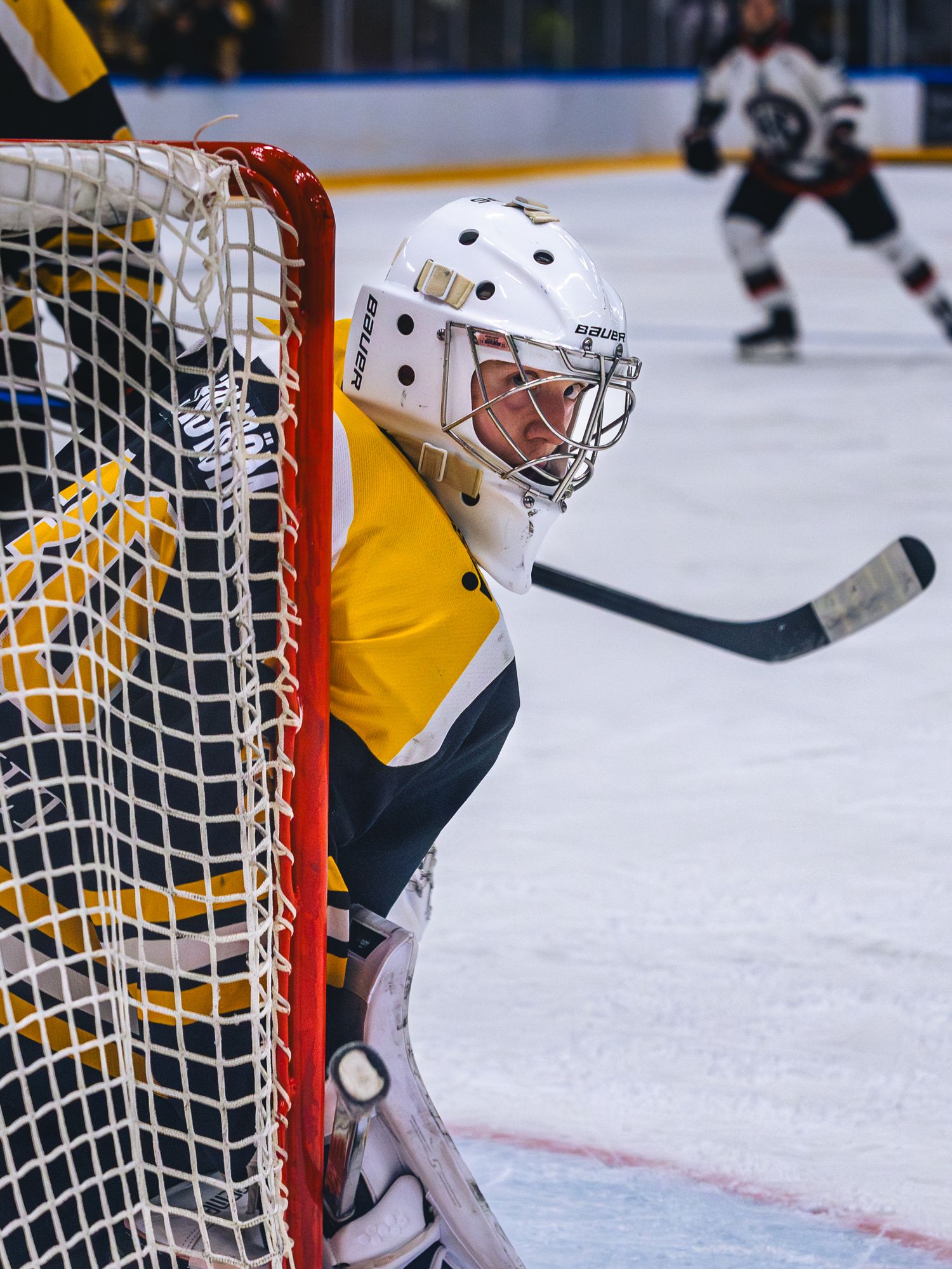 A goalie in yellow jersey protects the net during a hockey match.