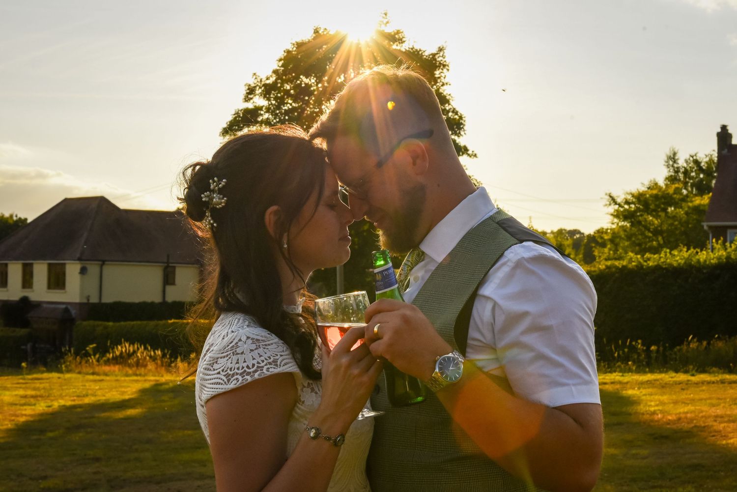 Romantic couple sharing a tender moment at golden sunset during outdoor wedding reception.