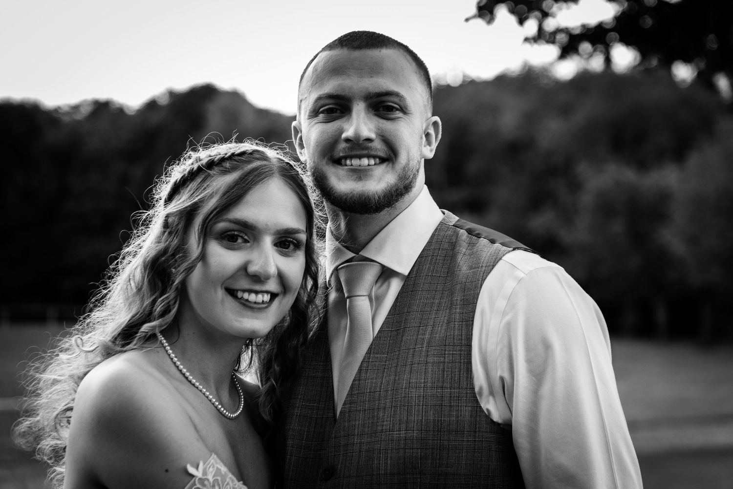 Black and white portrait of a smiling bride and groom outdoors at their wedding reception.