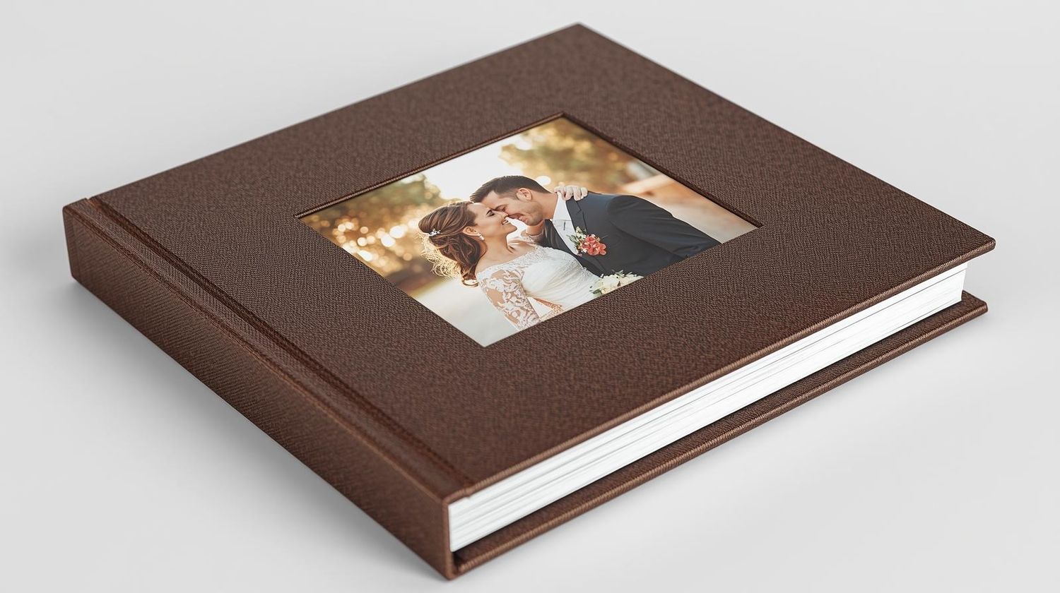 Brown leather wedding photo album with embossed cover featuring a romantic couple portrait in an elegant hardcover book.