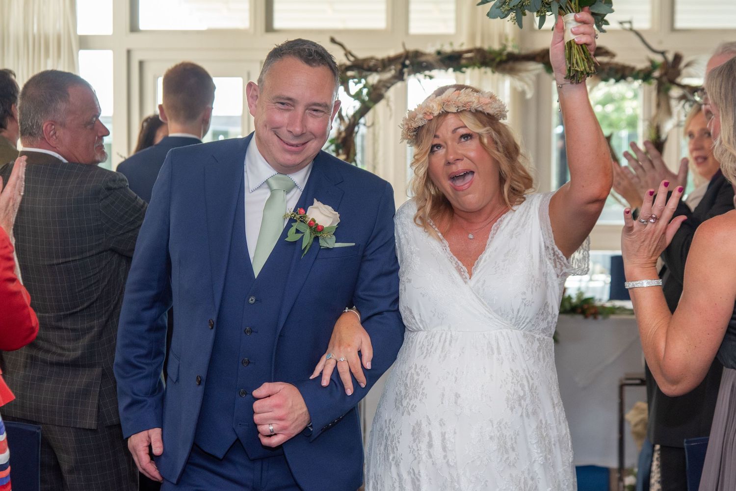 A group celebrates at an elegant indoor wedding reception with joyful dancing and laughter.