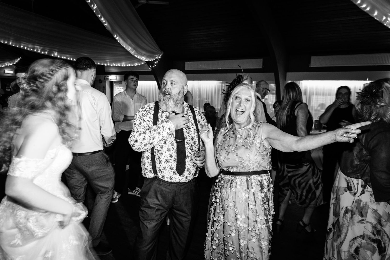 Guests dancing joyfully at a wedding reception in black and white photography.
