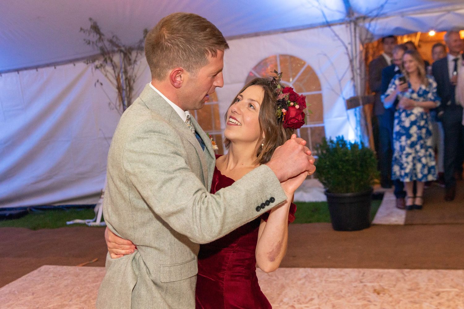 Couple sharing a romantic first dance at a wedding reception under a white tent.