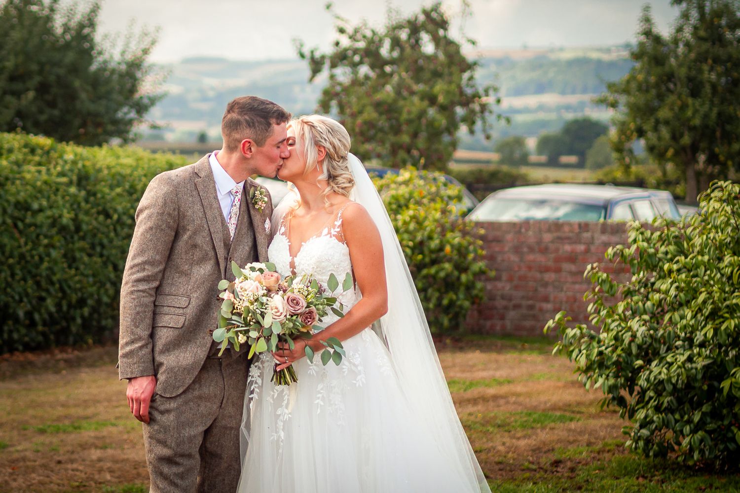 A couple shares an intimate moment during their wedding celebration overlooking a scenic mountain landscape.