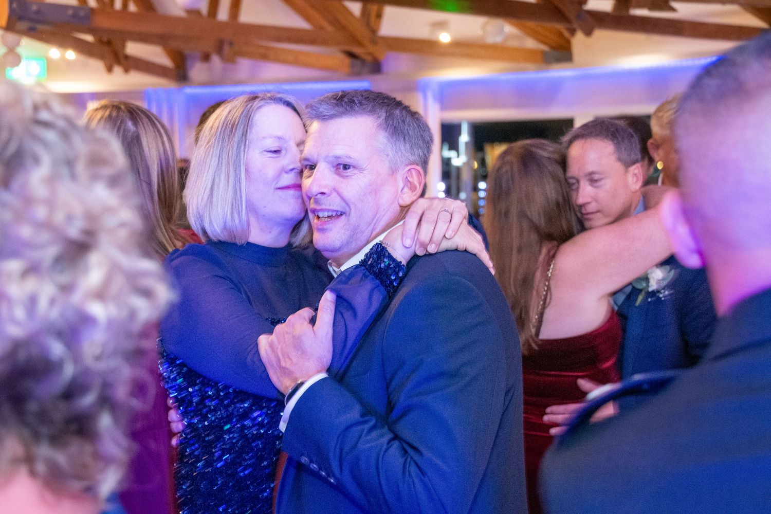Couple dancing and embracing joyfully on the dance floor at a formal wedding reception event.