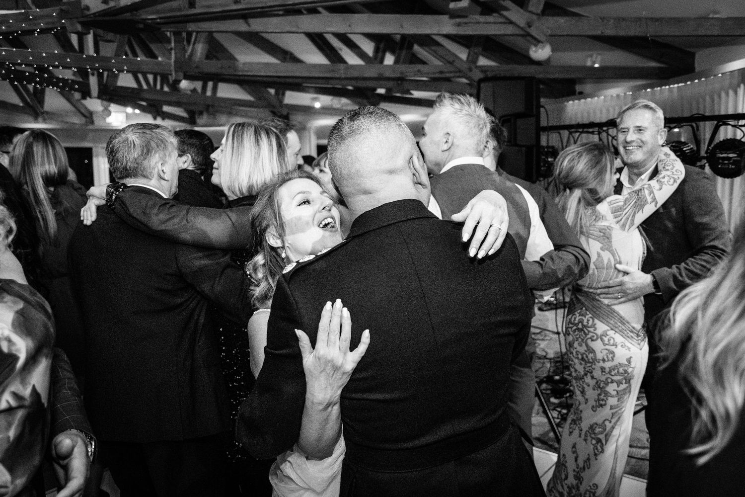 Guests laughing and dancing joyfully at a lively wedding reception celebration.
