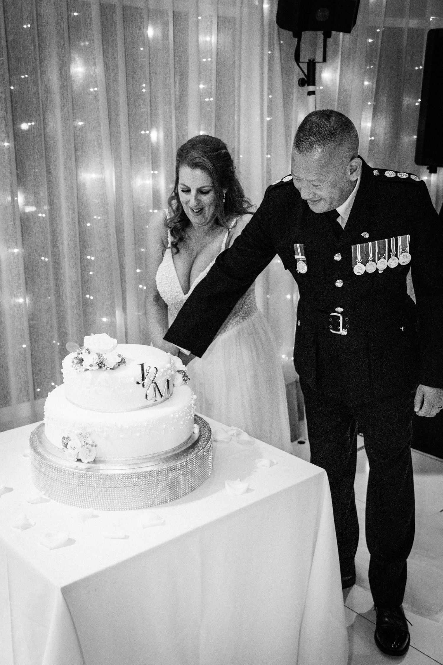 Bride and groom in military uniform cutting wedding cake at reception.