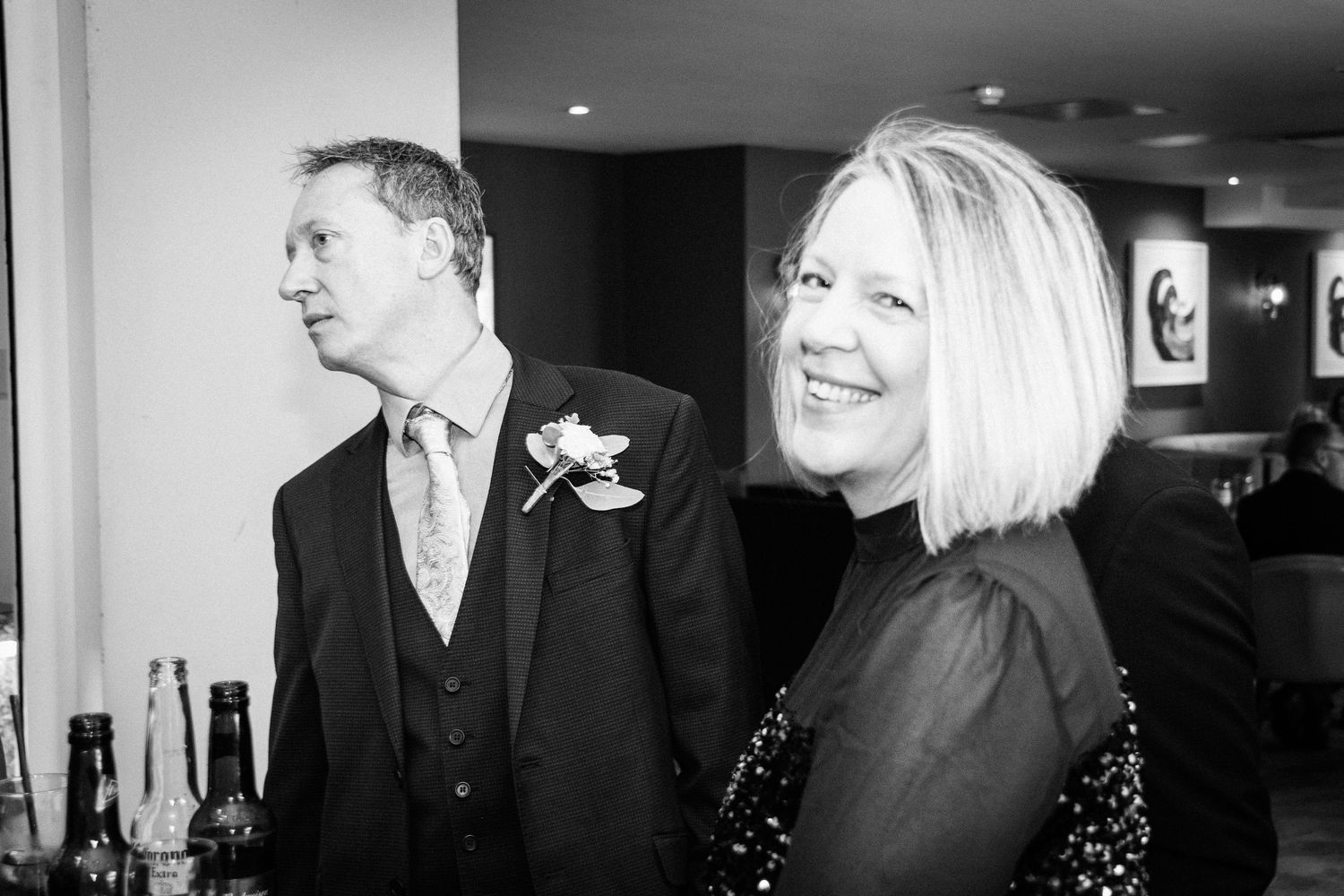Couple in formal attire smiling at a wedding reception in black and white.