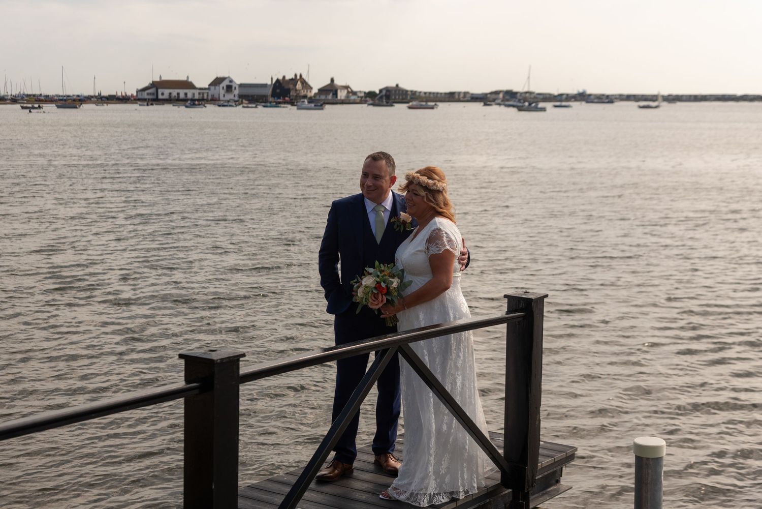 A couple sharing a romantic moment on a waterfront dock at sunset.