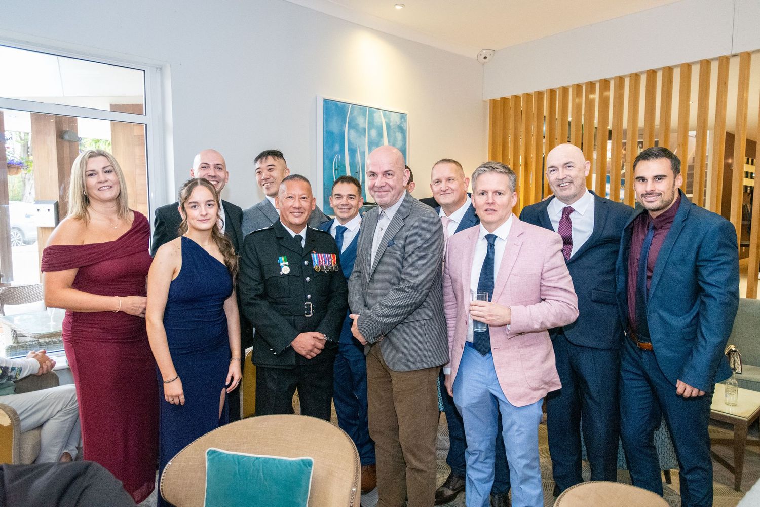 Group of elegantly dressed guests posing together at a formal military wedding reception event.