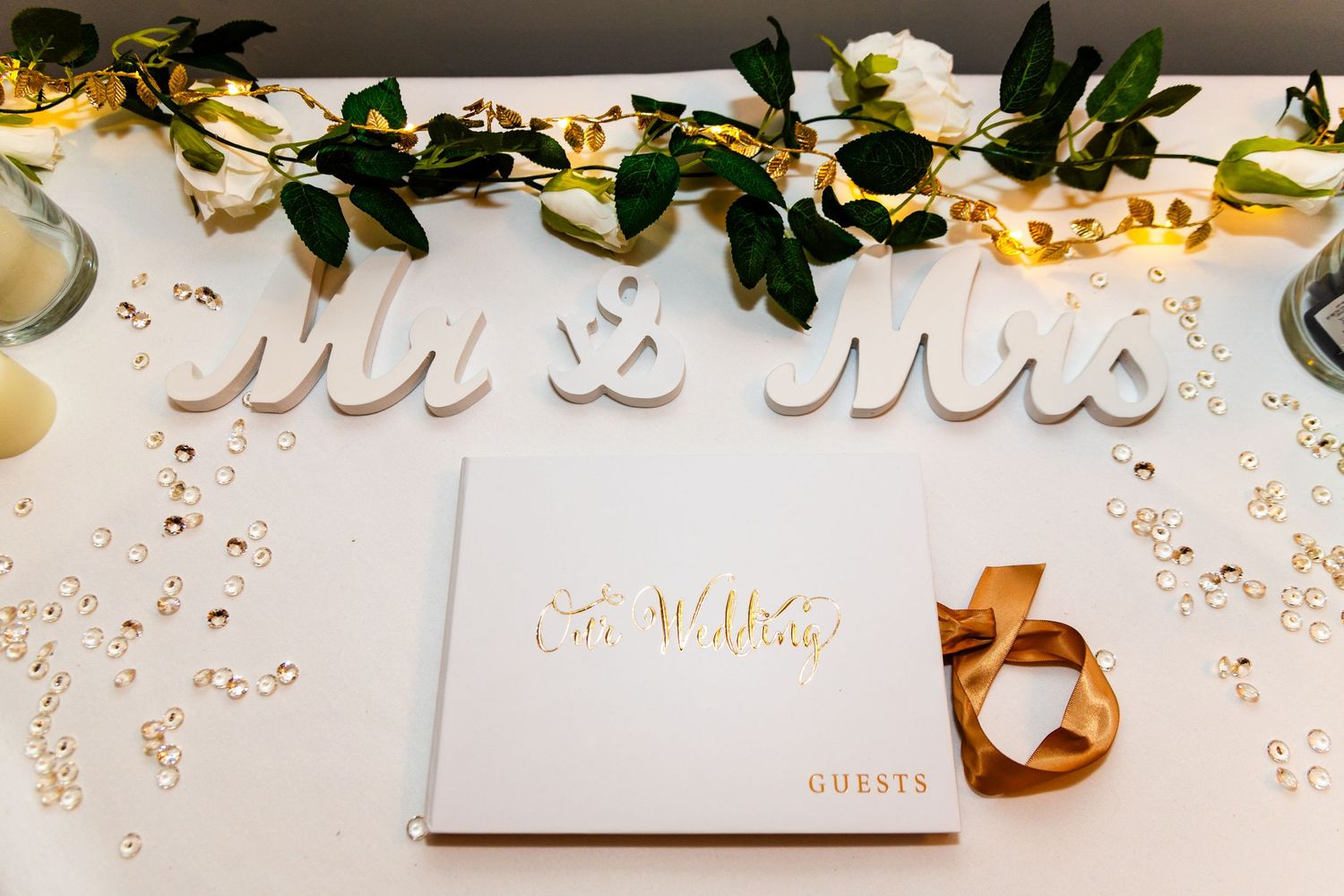 Elegant wedding reception table decorated with white floral arrangements, greenery, and romantic candlelight.