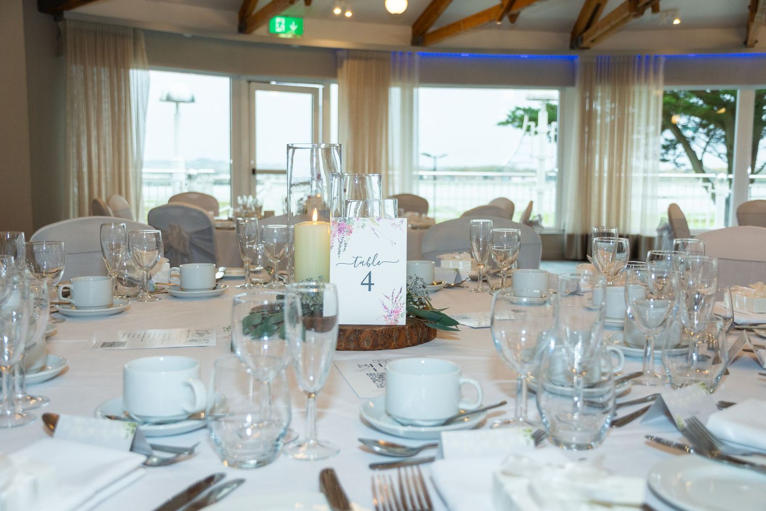 Elegant wedding reception venue with round tables set with white linens, glassware, and floral centerpieces.