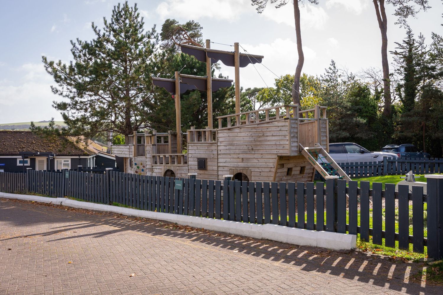 A series of wooden fences with metal railings line a pathway along a residential property.