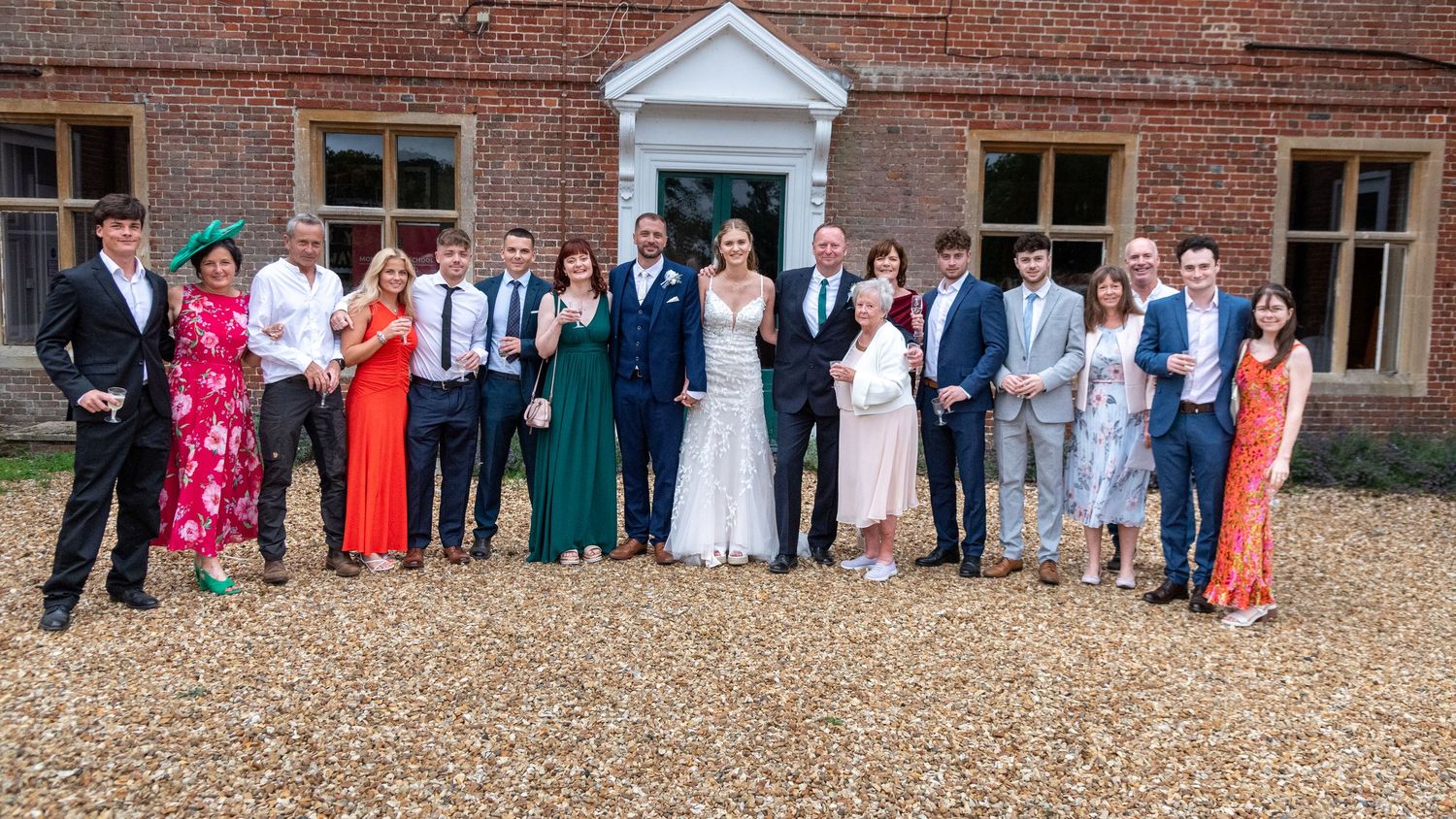 Wedding party group photo outside elegant brick manor house with bride and groom.