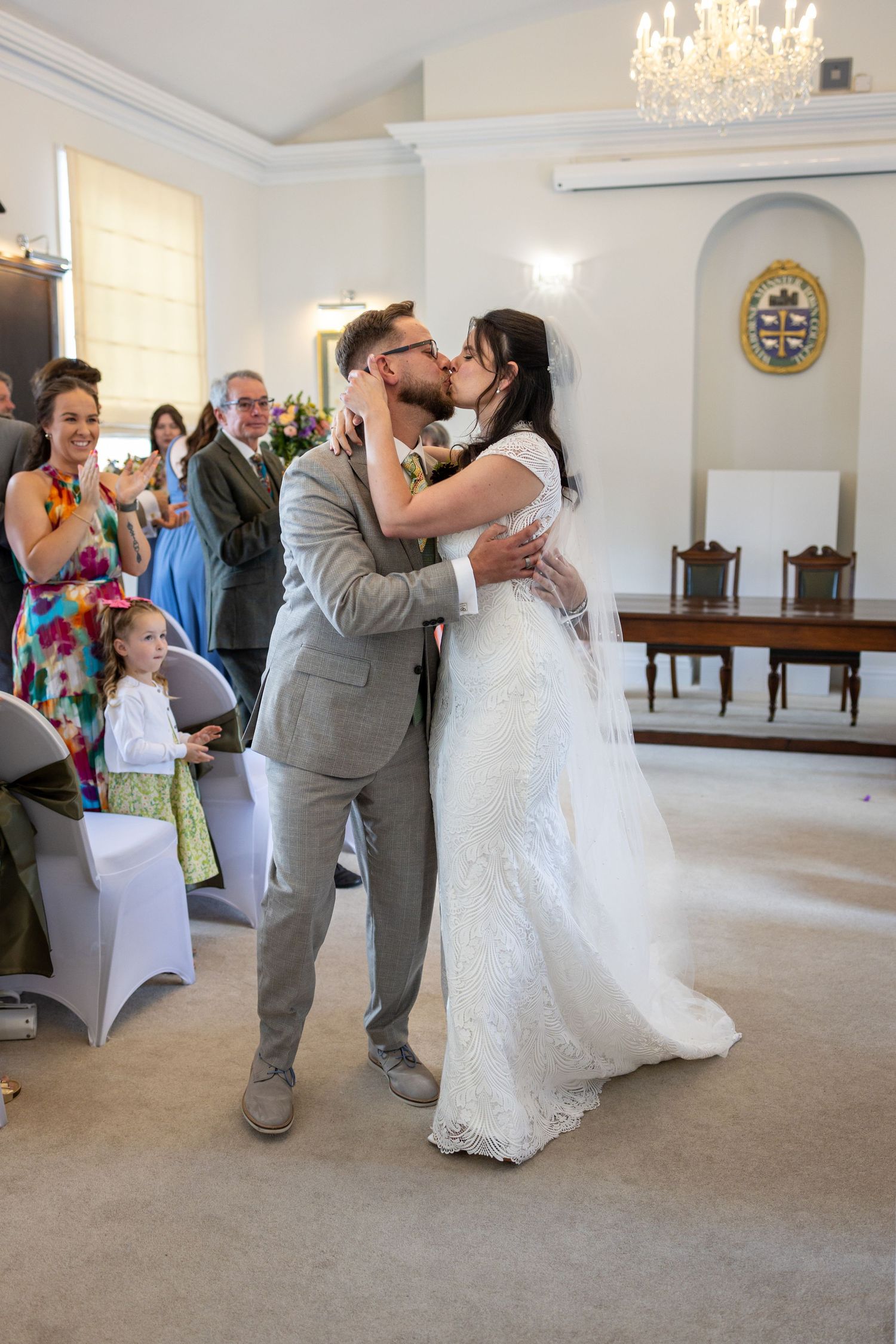 Bride and groom share their first kiss as a married couple during their wedding ceremony indoors.